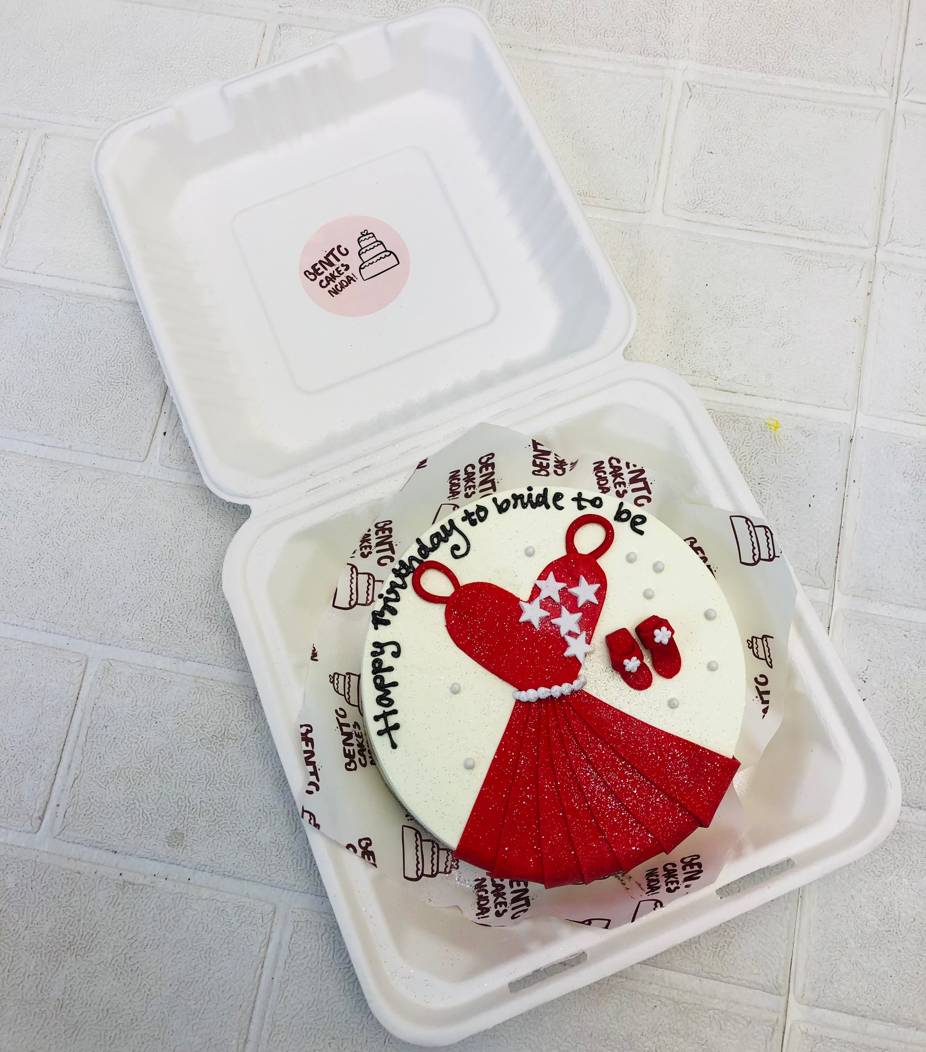 A white bento cake with bridal red frock and sleepers, designed for bride to be.