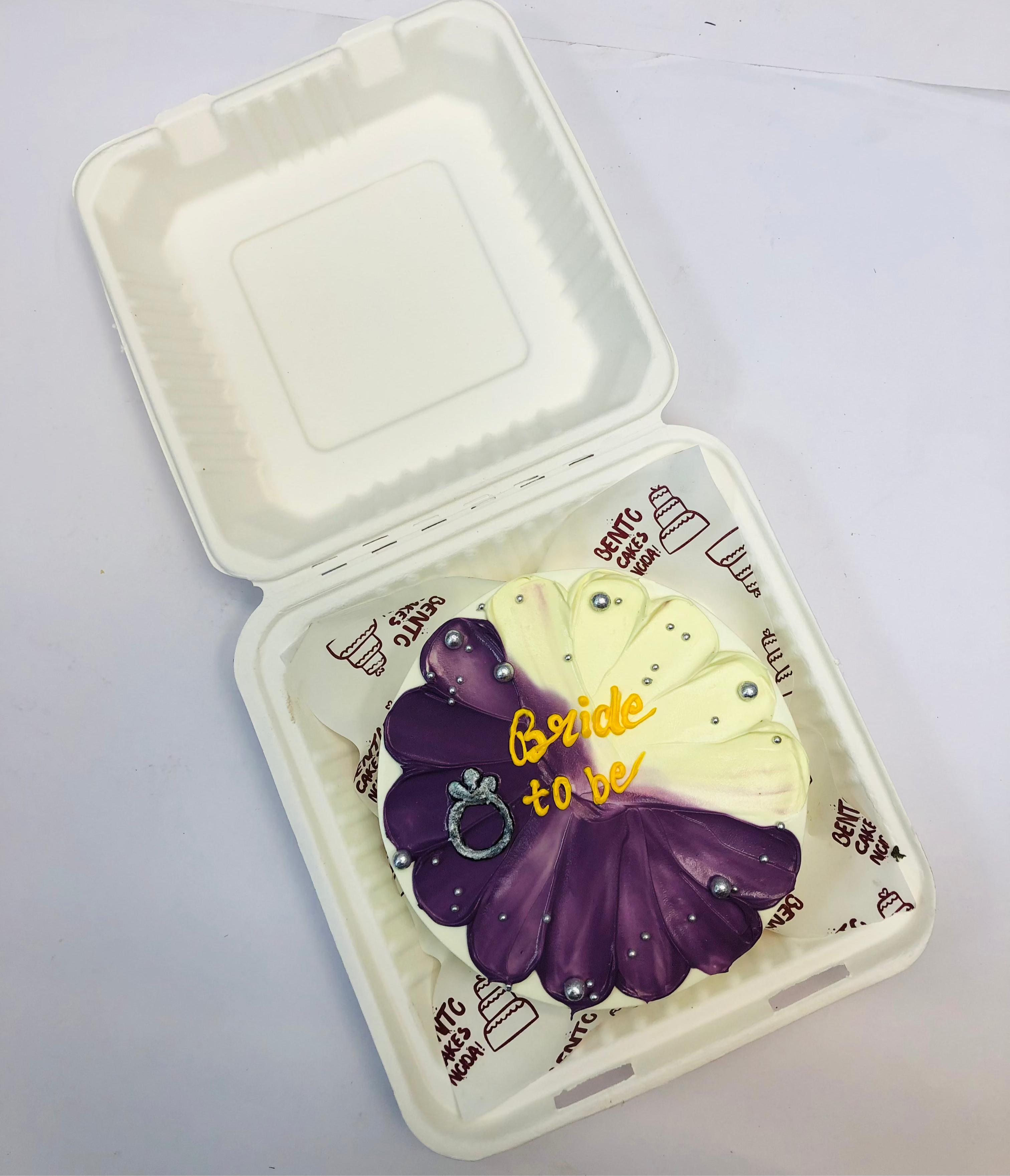 A white bento cake with purple and offwhite floral design for bride to be.