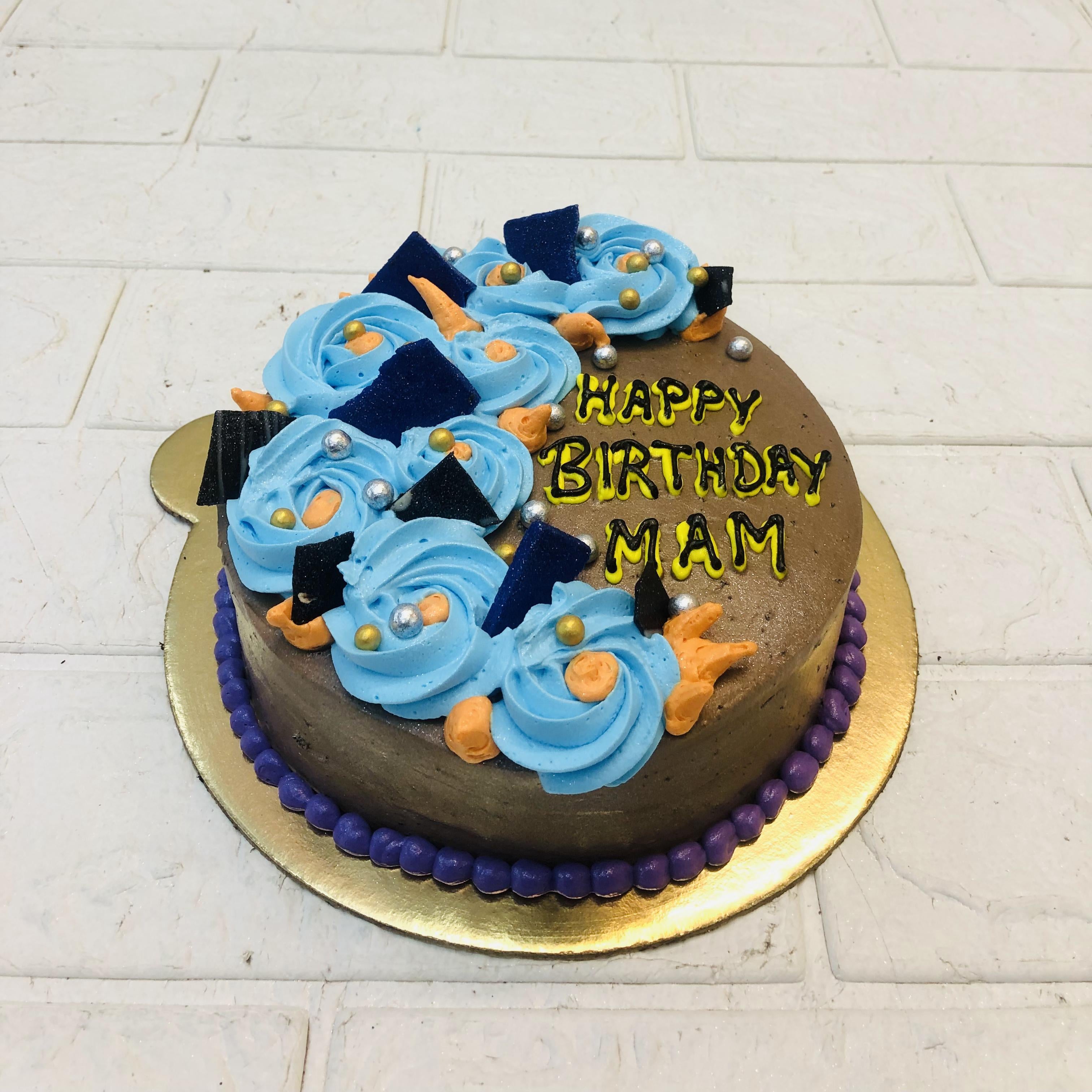 A chocolate cake designed with blue floral design and blue nuts.