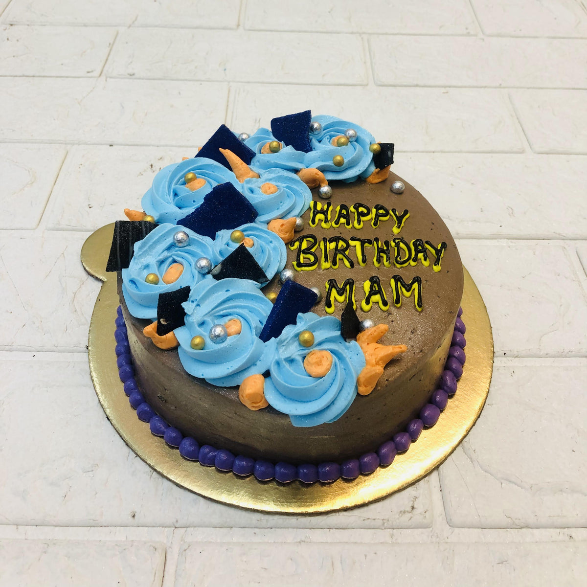 A chocolate cake designed with blue floral design and blue nuts.