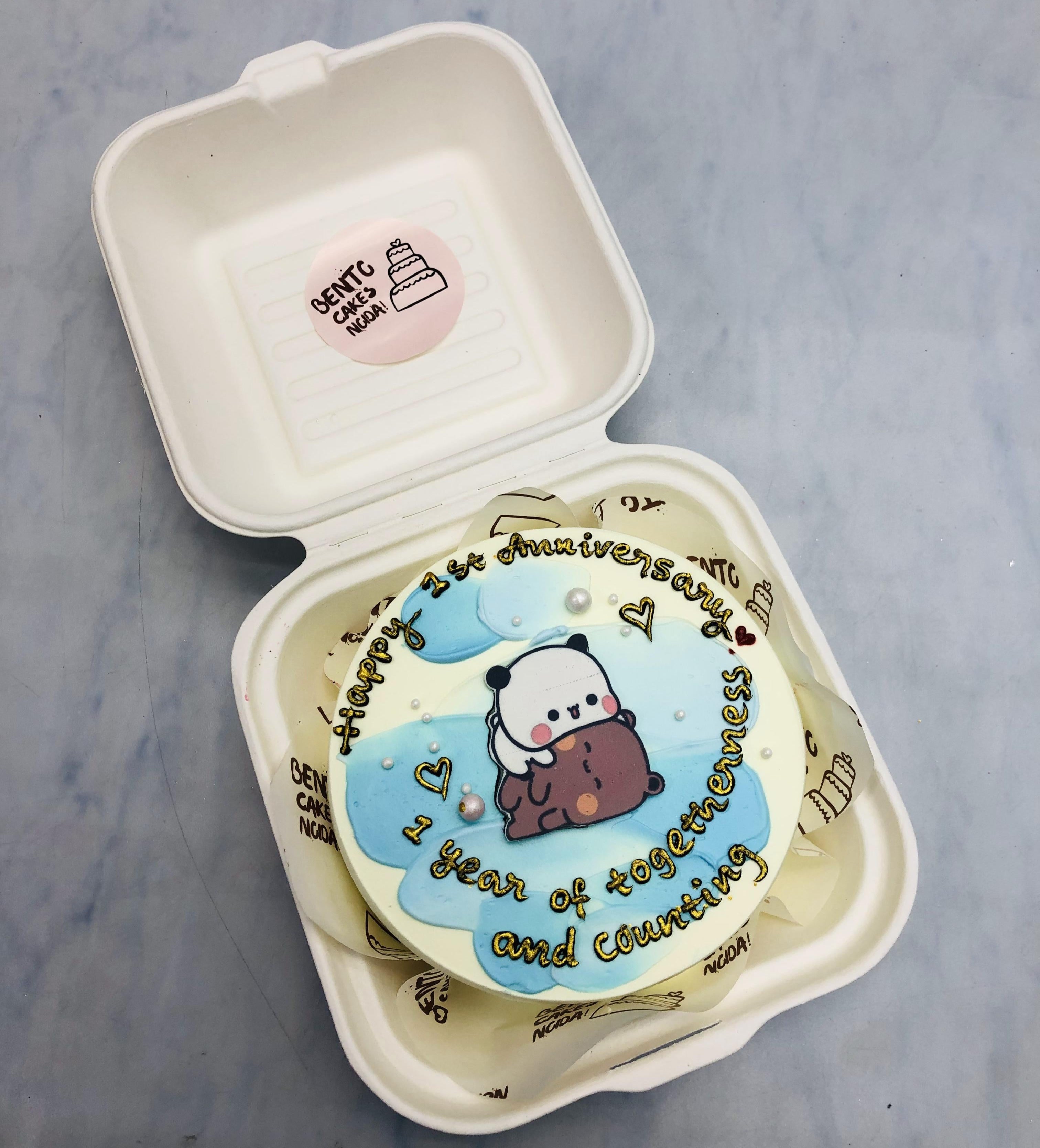 An offwhite cake with cute bubu dudu kissing print and designed for anniversary in golden text.