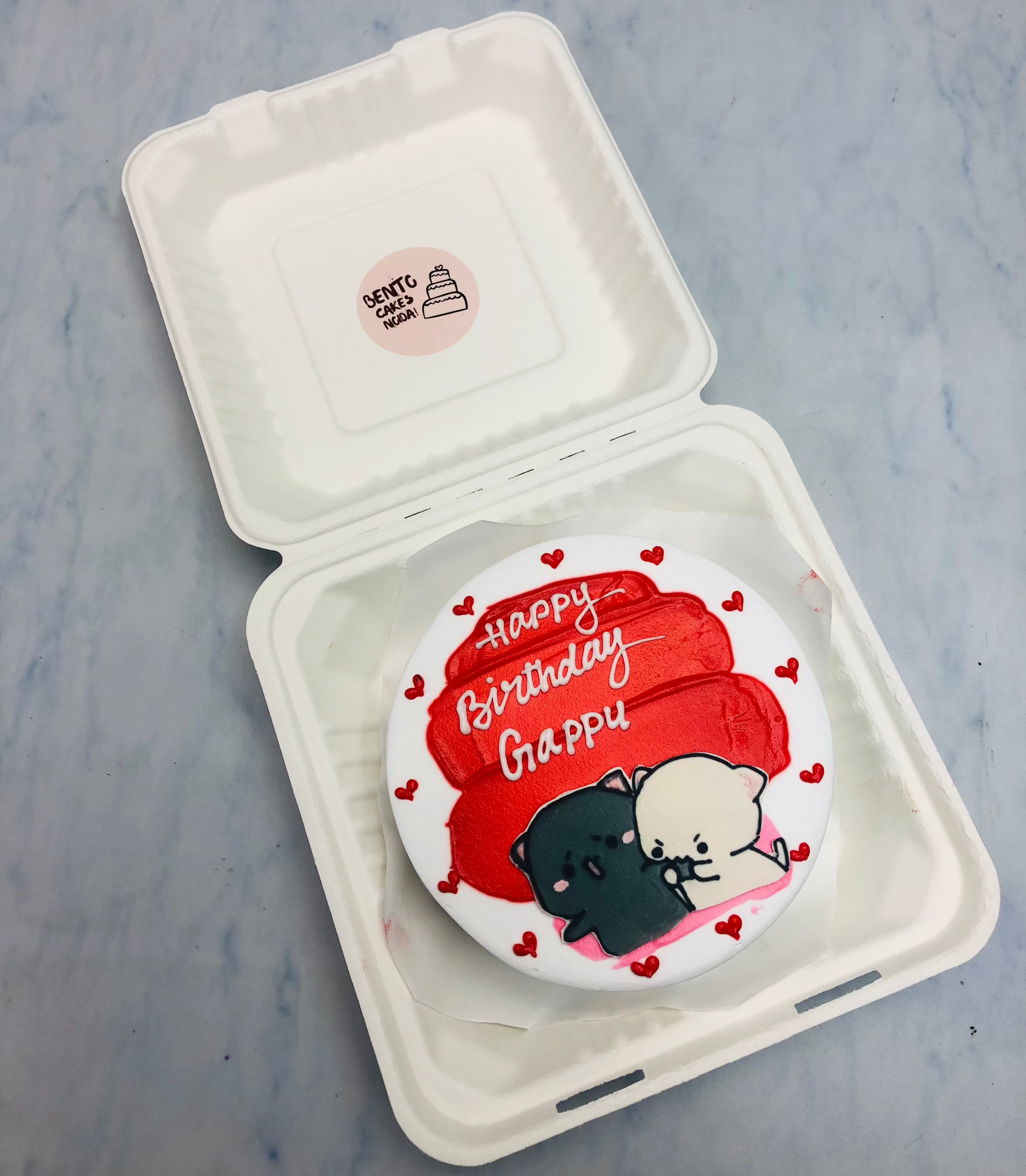 A white bento cake having red shades and loving bubu dudu caroon print.