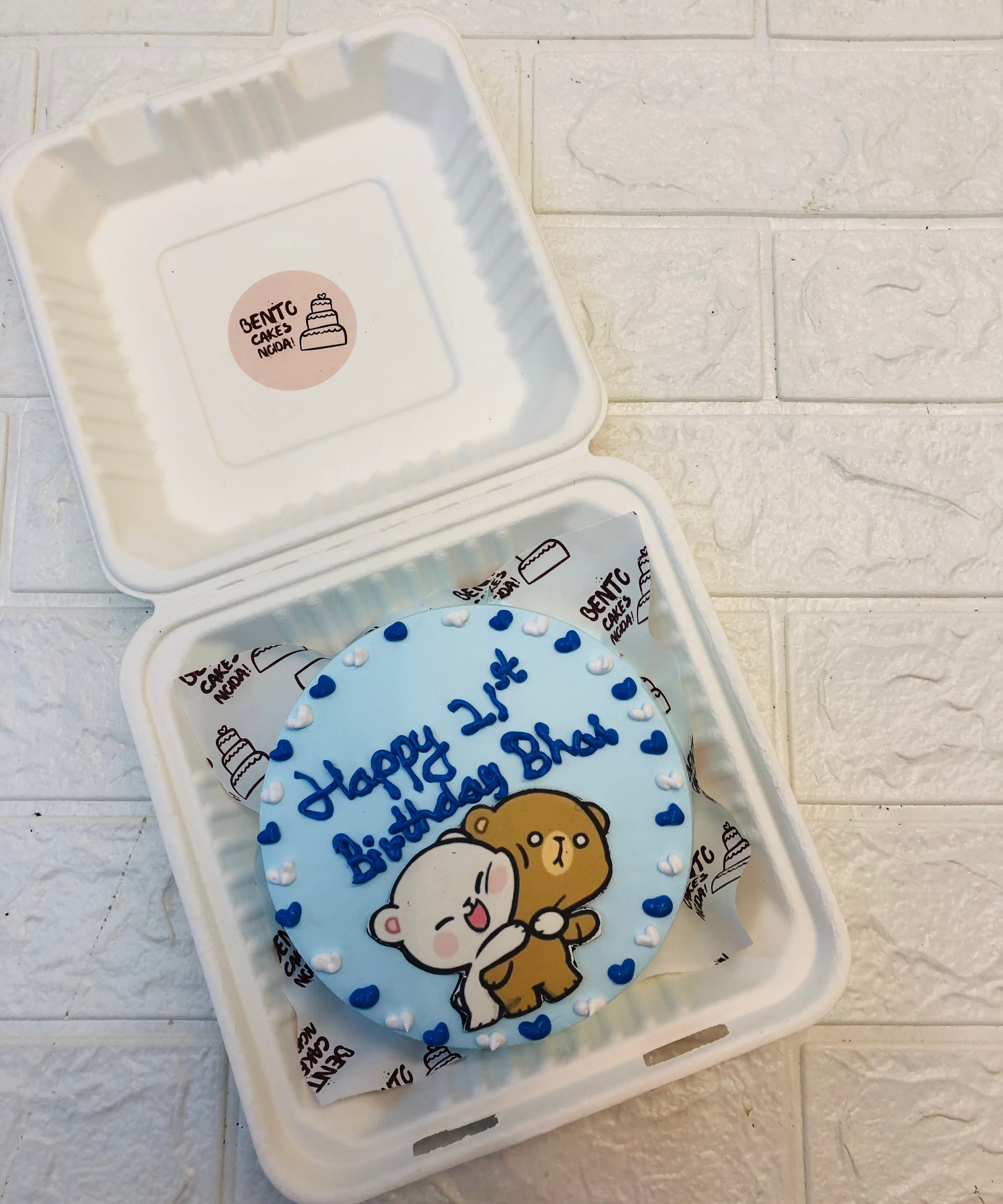 A light blue bento cake with hugging bubu dudu loing cartoon print, deorated with blue and white hearts design.