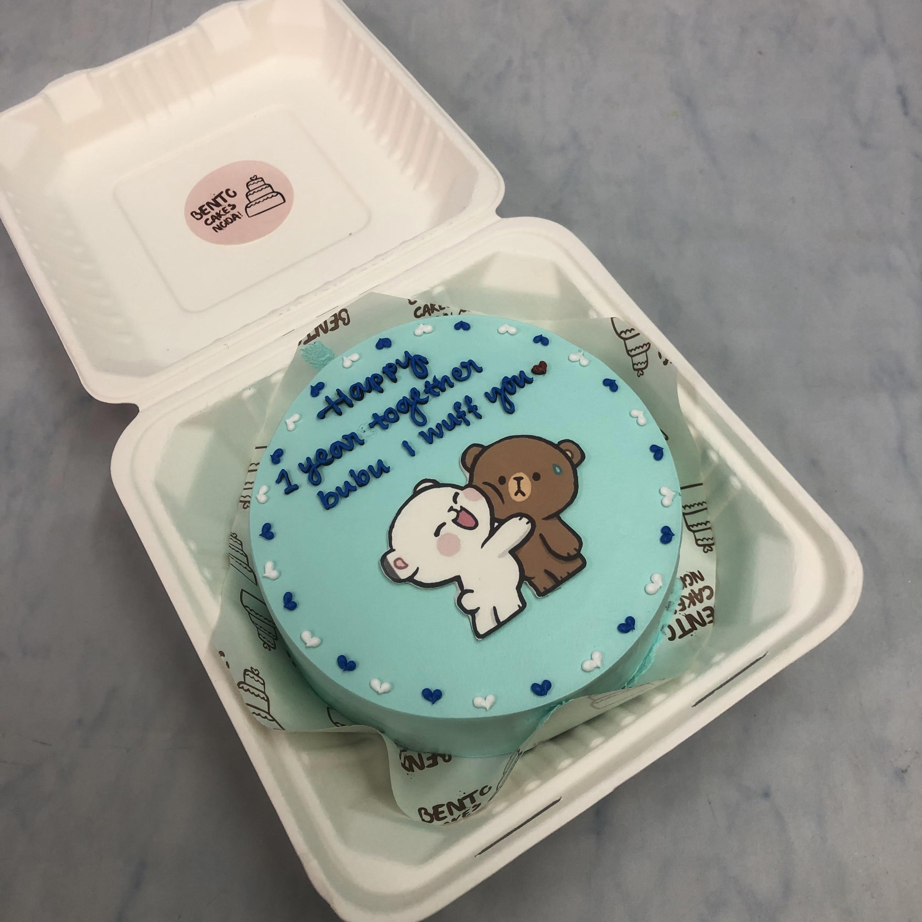 A light blue bento cake with kising bubu dudu print and decorated with blue white hearts design.