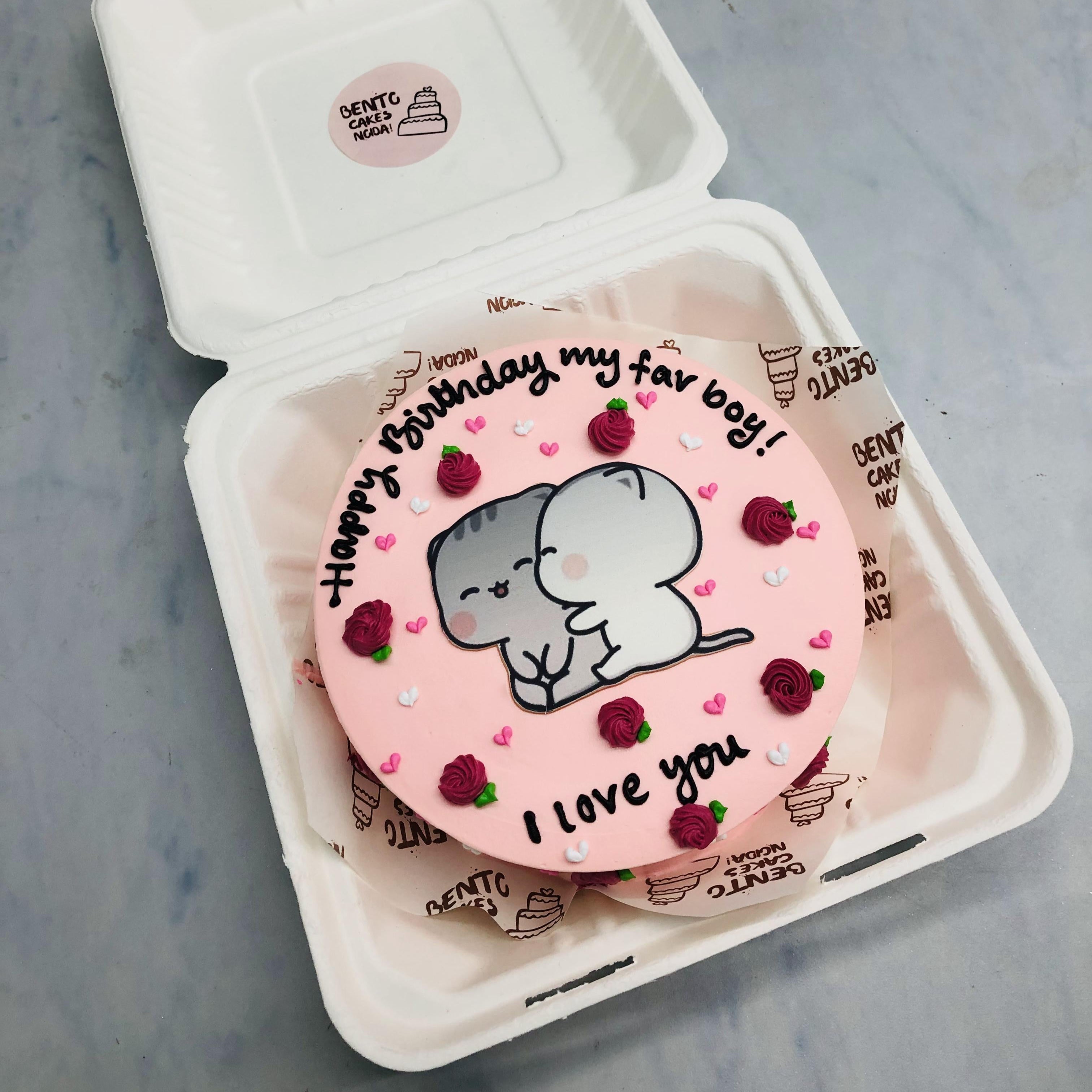A light pink cake decorated with red roses design and a ubu dudu cartoon printed on it and having some beautiful text written on it with black icing.