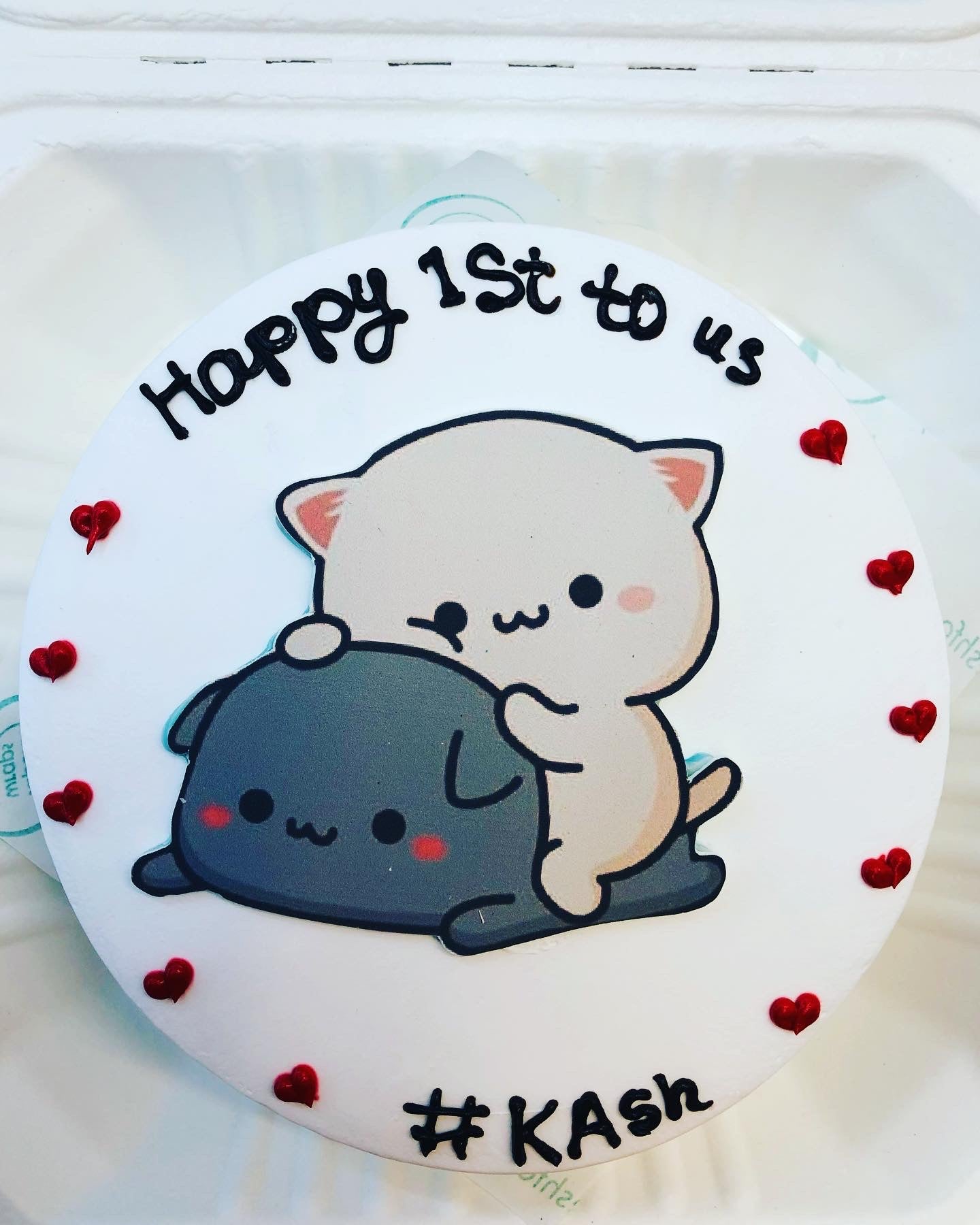 A white bento cake cake having blue white bubu ddu print and surrounded with red hearts.