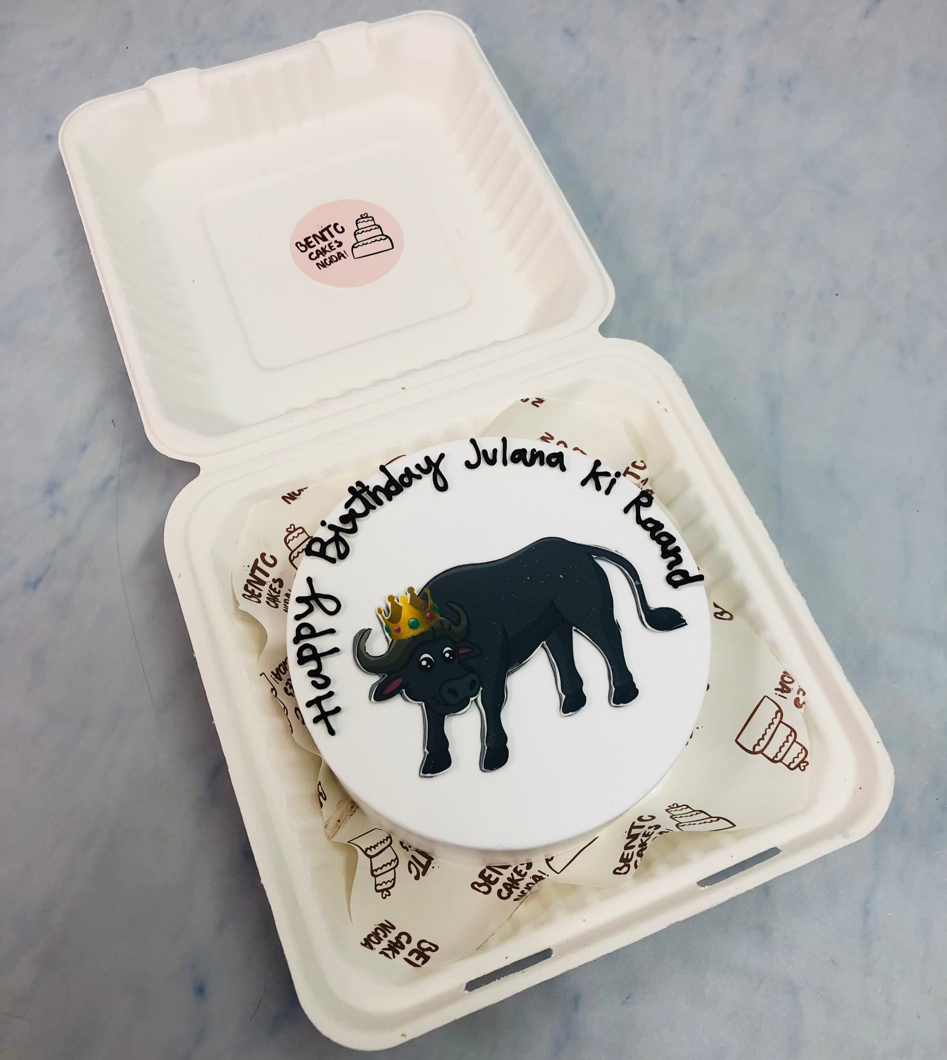 A white bento cake having a buffalo print and designed for celebrating her birthday. 