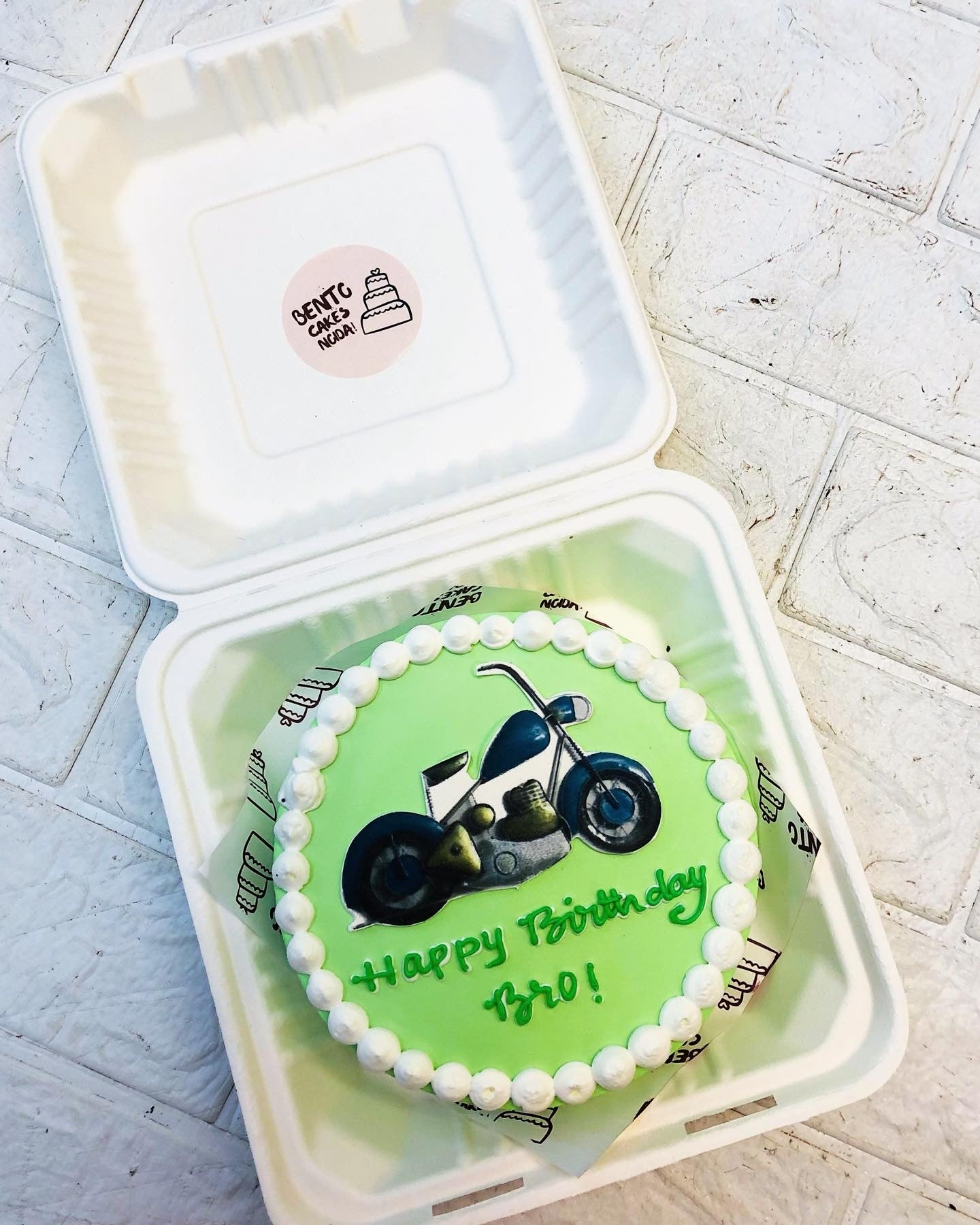 A lime green bento cake with a bullet lover bike rint on it.