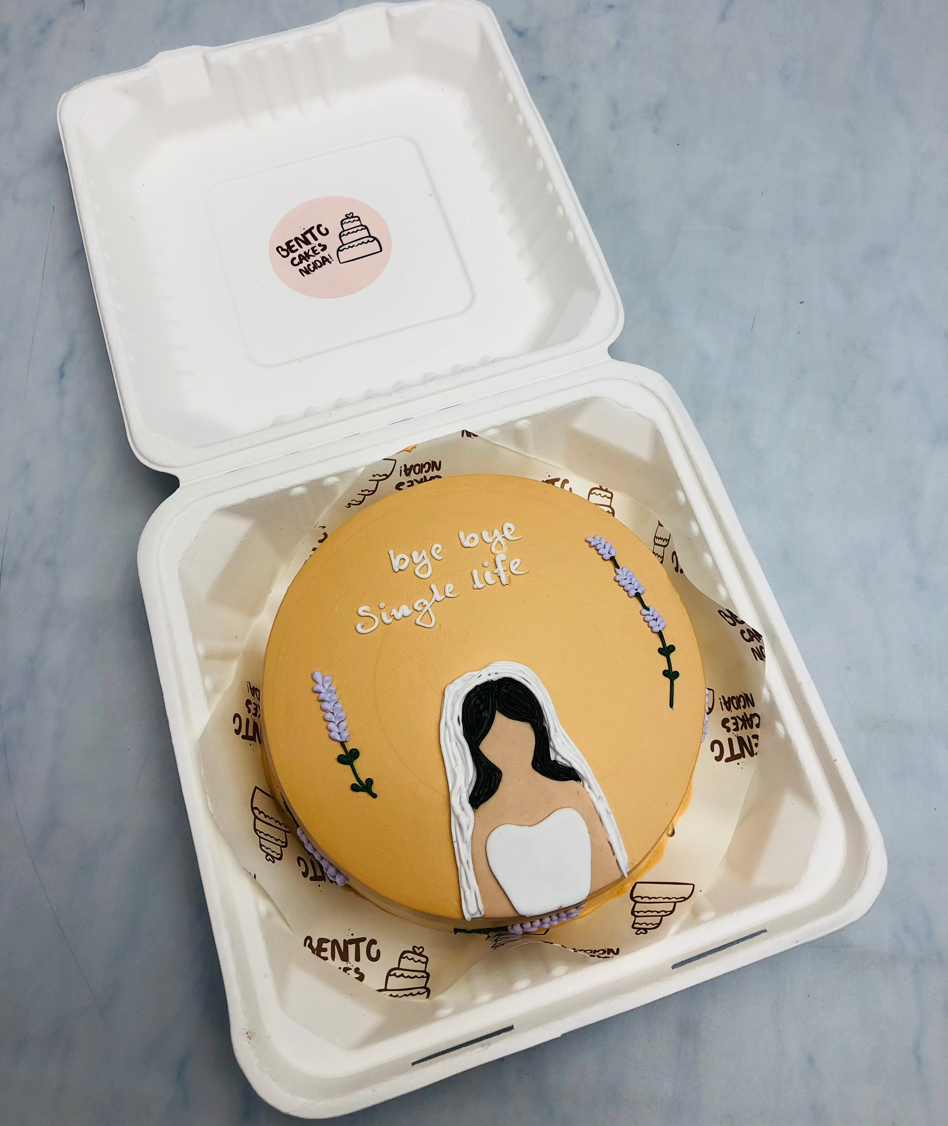 A light brown cake with a bridal girl design and a text "bye bye single life" written with white icing.