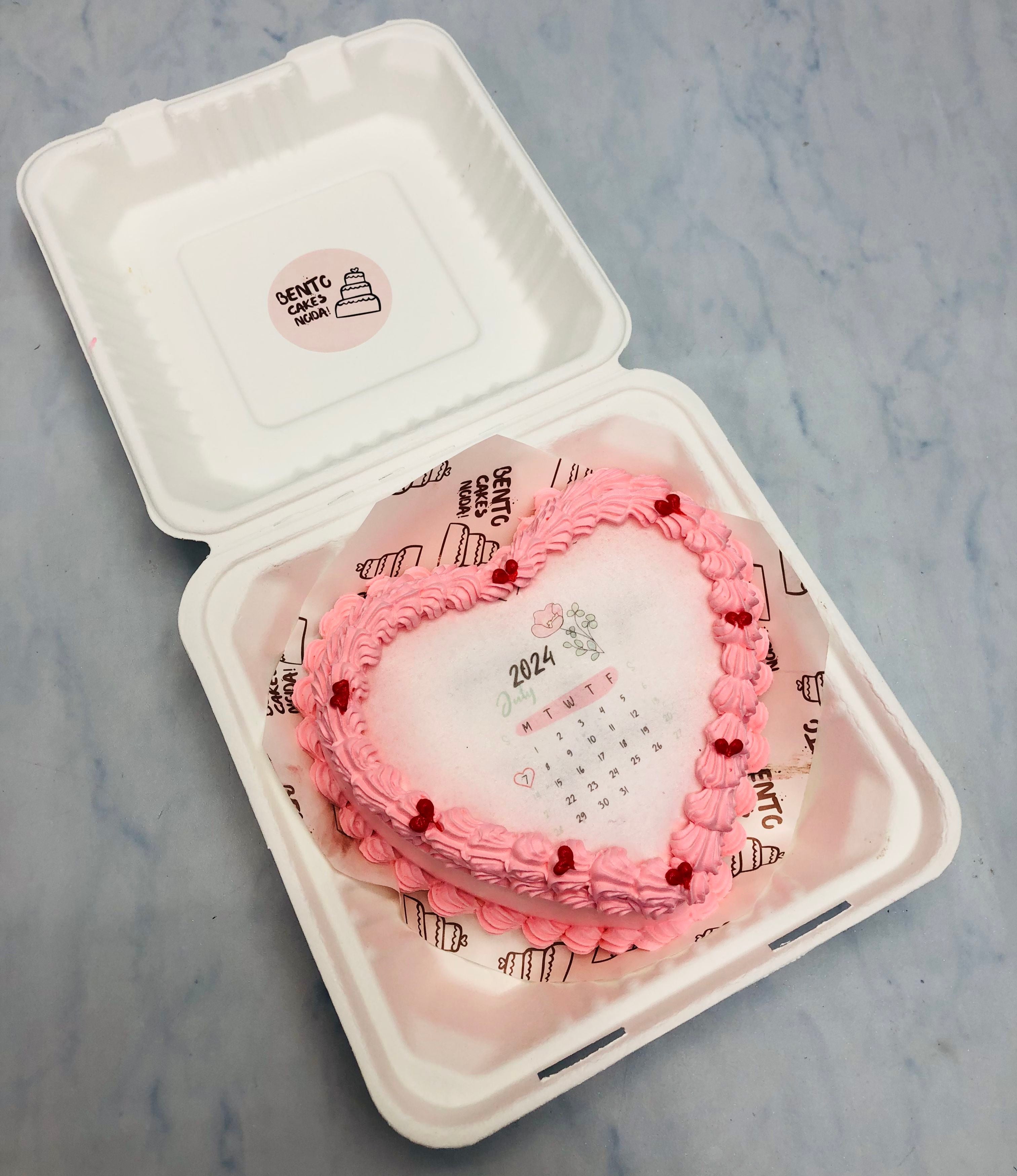 A pink heart shape fire bento cake withb calendar design.