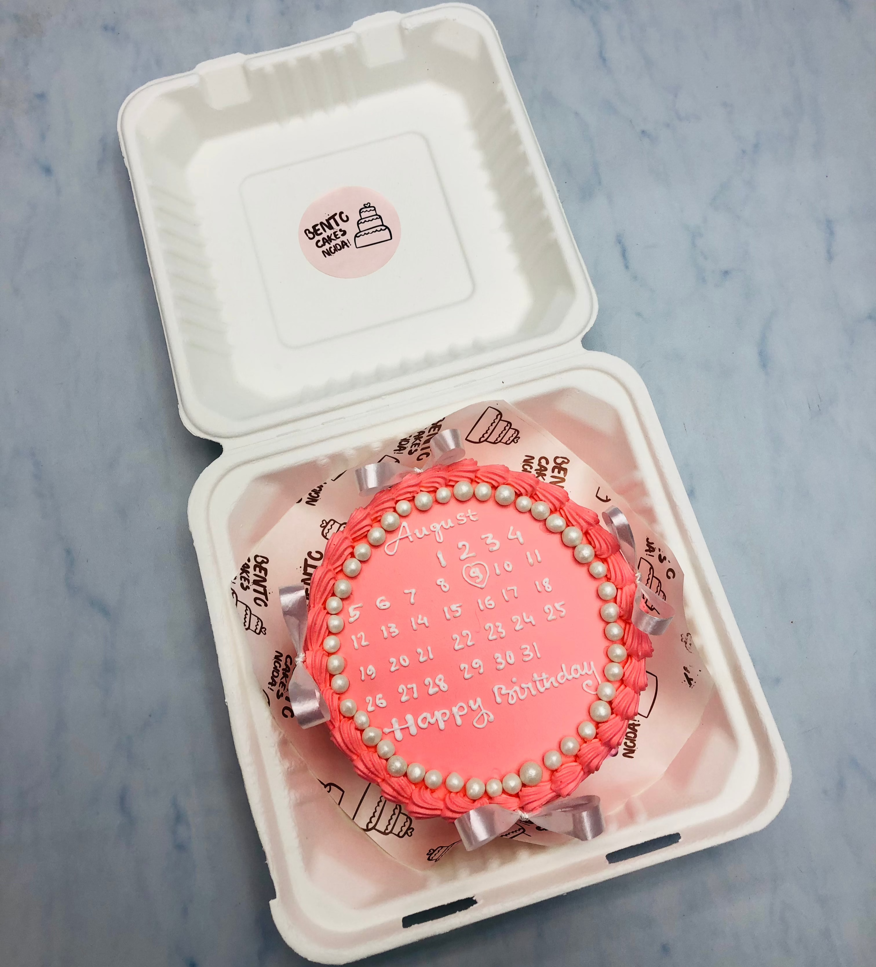 A orange bento cake having calendar design for birthday celebration.