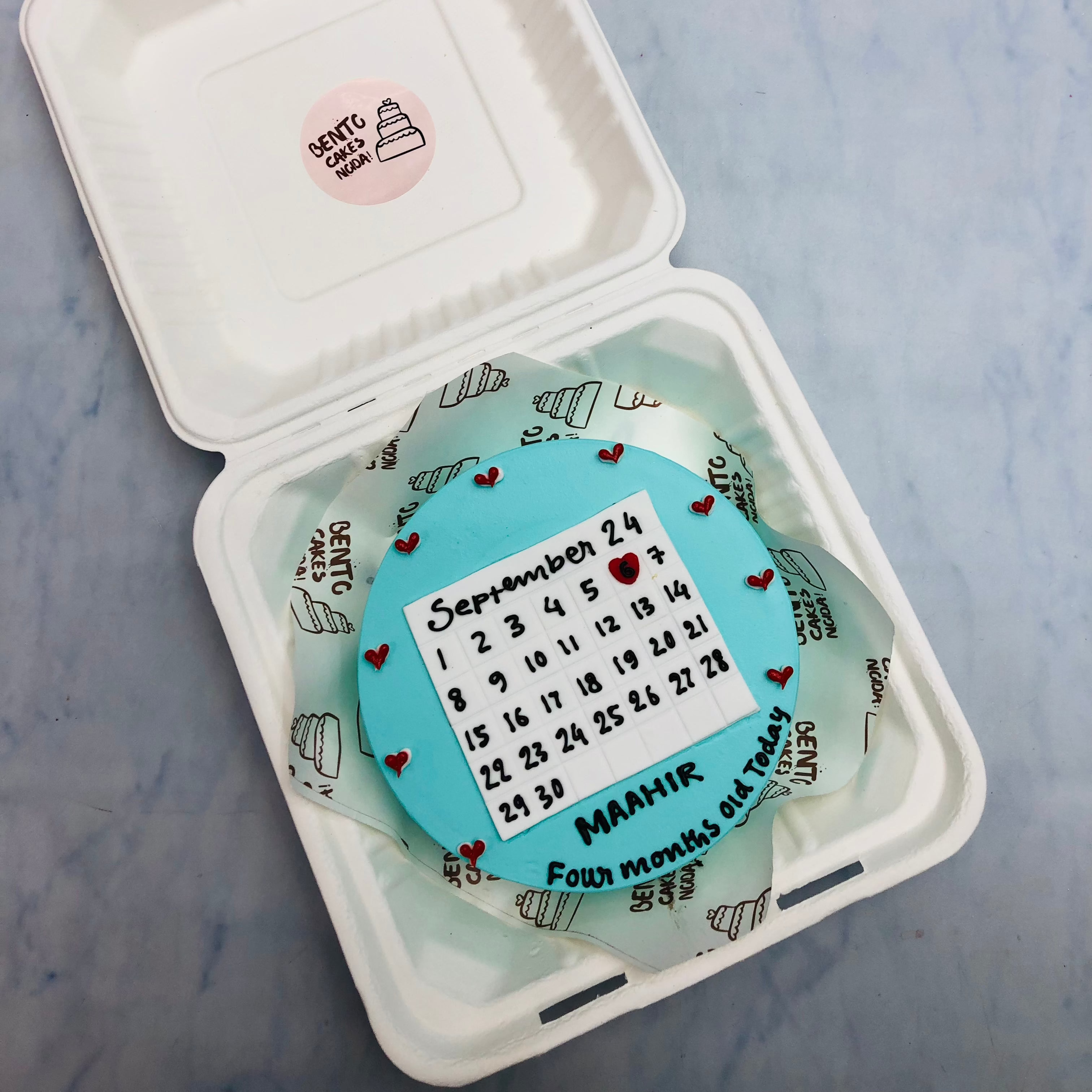 A sky blue bento cake with a calendar theme for 4 months baby birthday.