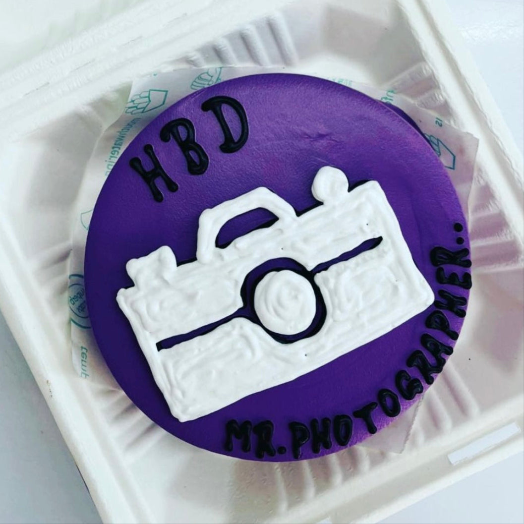 A cake placed inside a bento box, accompanied by a camera resting on top of it.