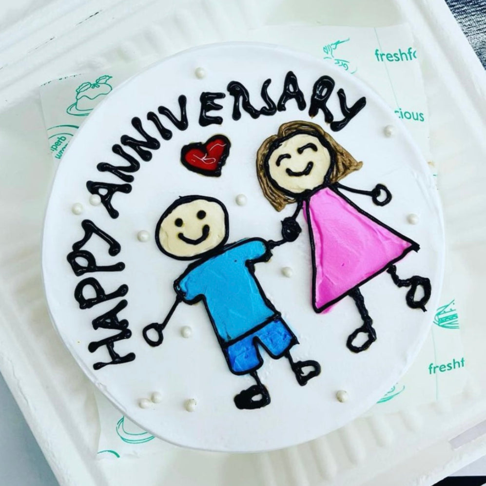 A beautifully decorated cake featuring a joyful couple on top, presented in an elegant box.