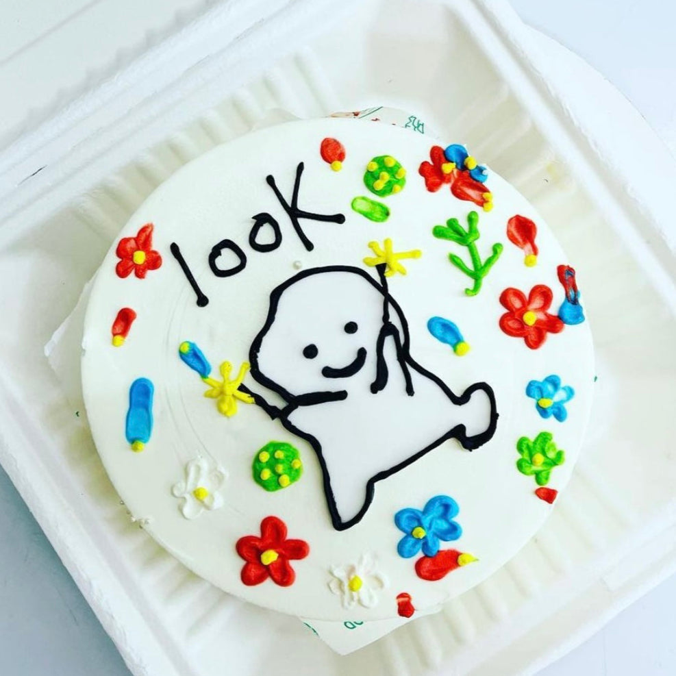 A colorful cake topped with a cartoon character, enclosed in a transparent plastic container for freshness.