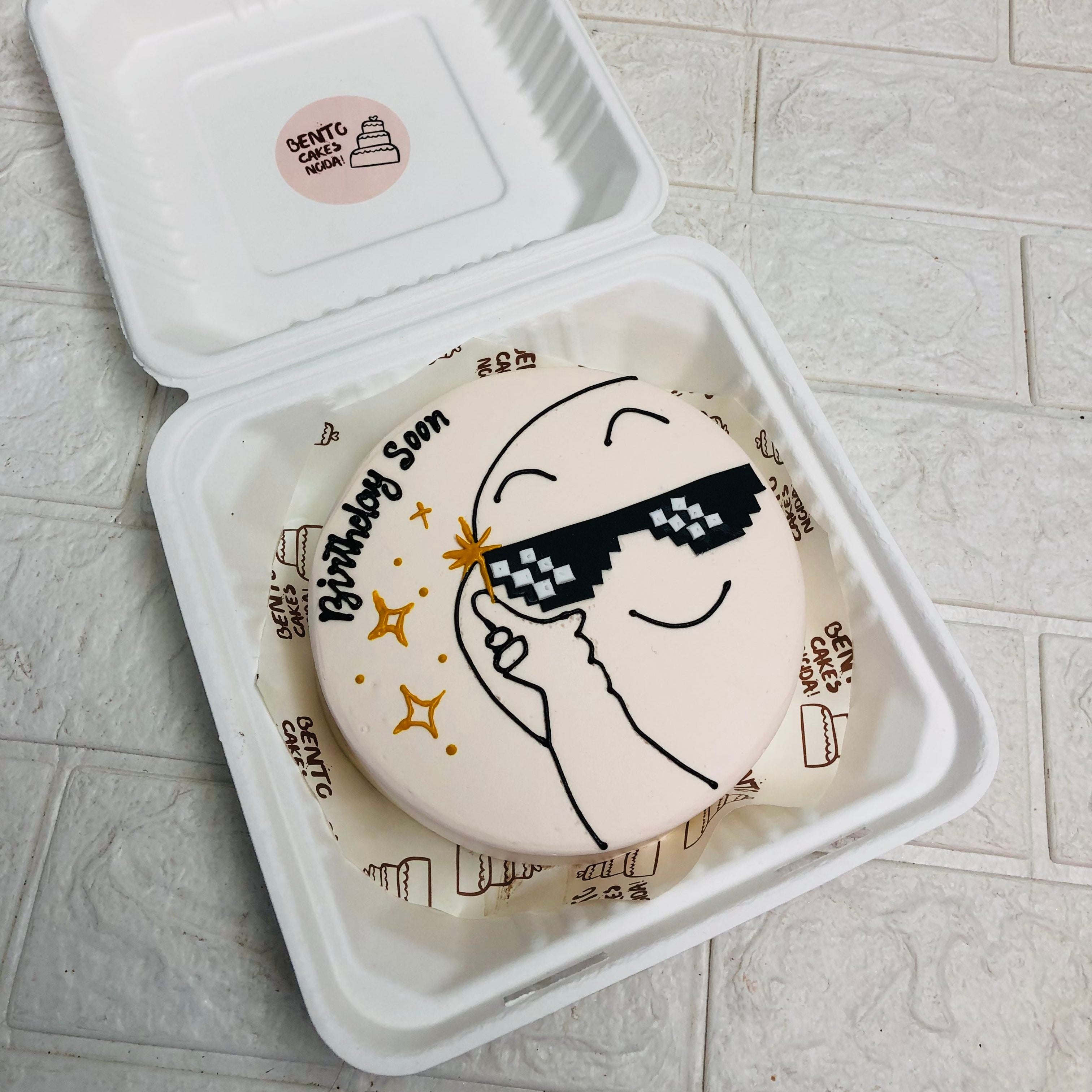 A cake in a box featuring a colorful cartoon character design on the top, ready for celebration or gifting.