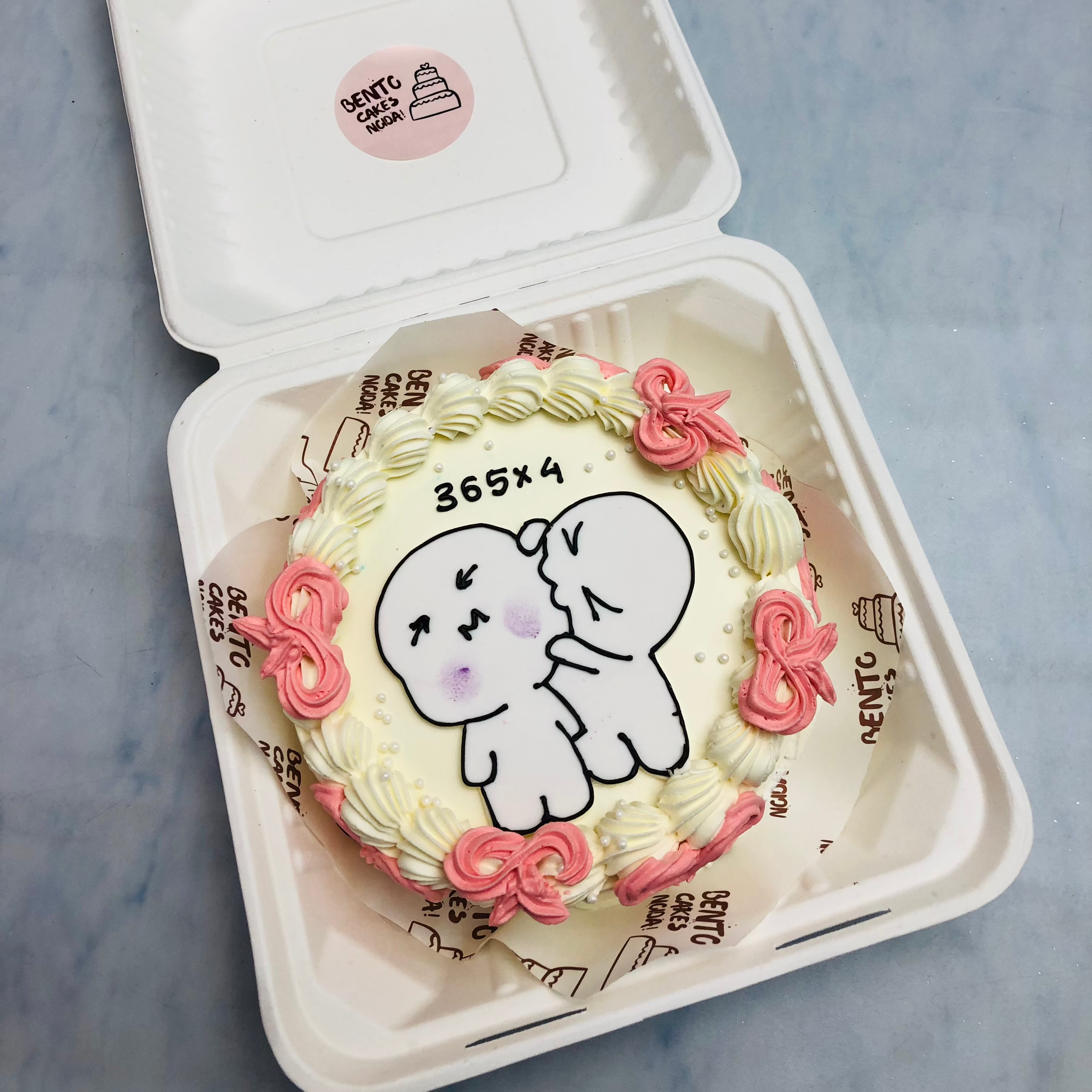 A light yellow round cake with biting cartoon print on t and decorated with pink creamy bows.
