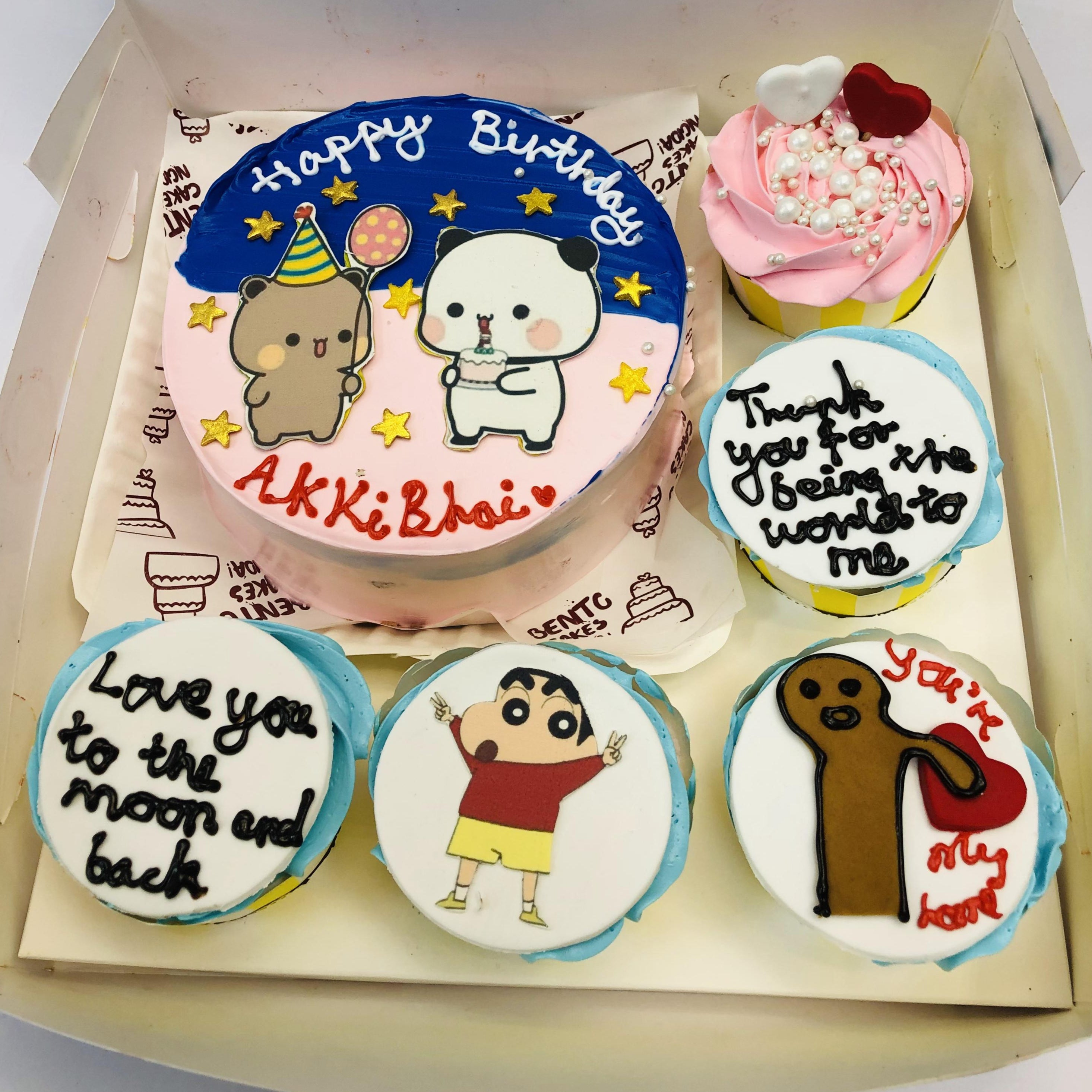 A cartoon-themed bento cake combo, featuring a main round cake with a colorful background and adorable cartoon characters, accompanied by five cupcakes with unique messages and designs, all arranged in an elegant box.