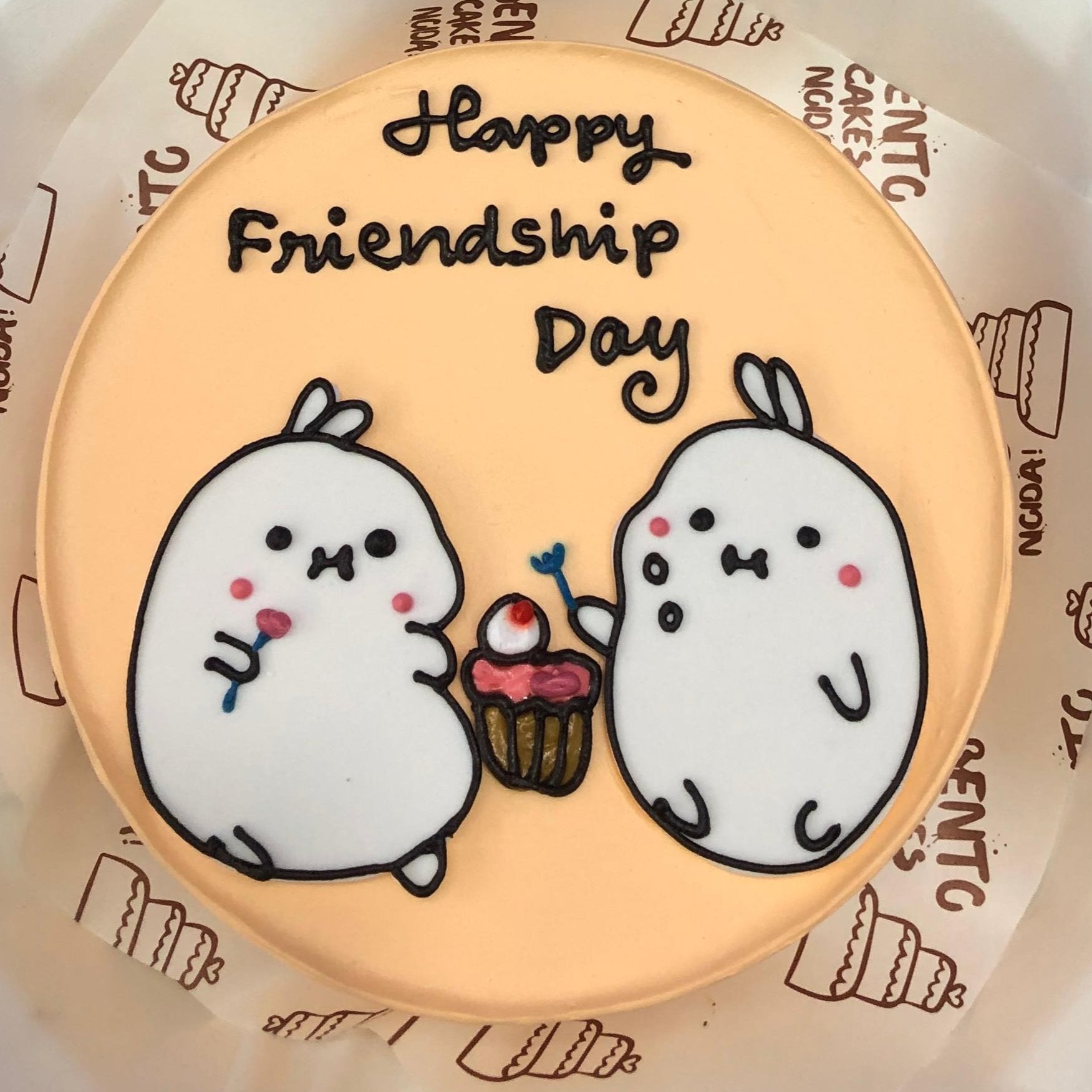 A peach color bento cake havive 2 cute characters celebrating friendship day.