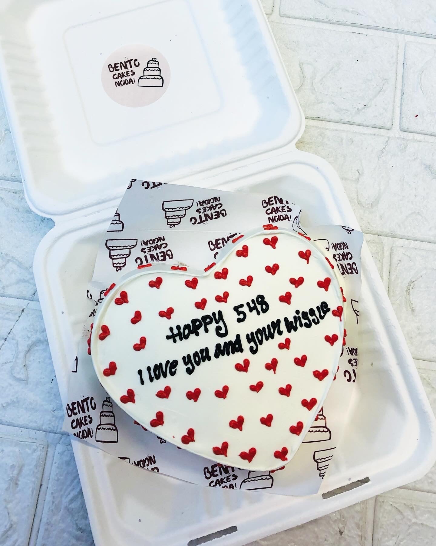 A white heart cake with full or red hearts all over the cake.