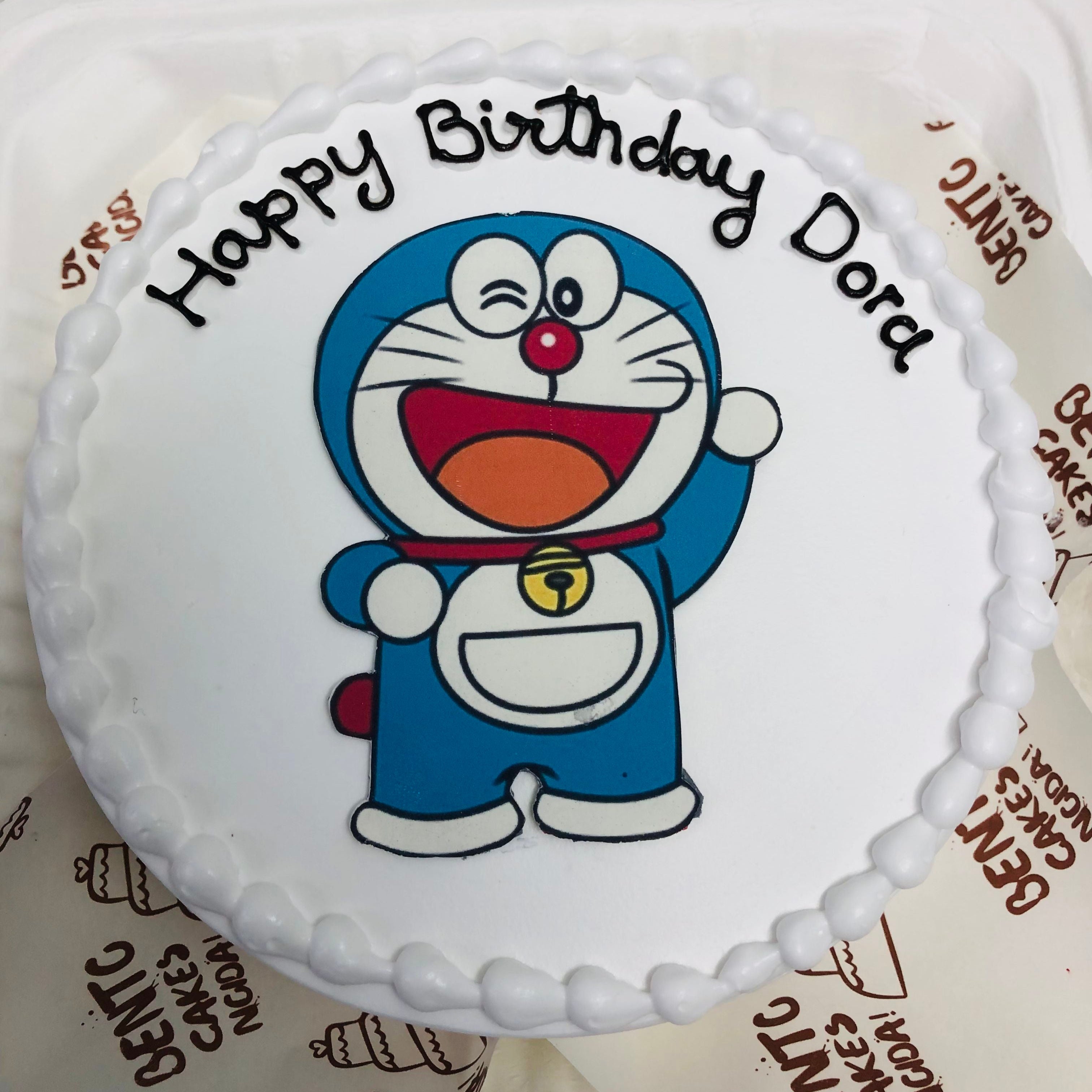 A colorful cake topped with a cheerful Doremon cartoon with front view, perfect for a fun celebration or birthday party.