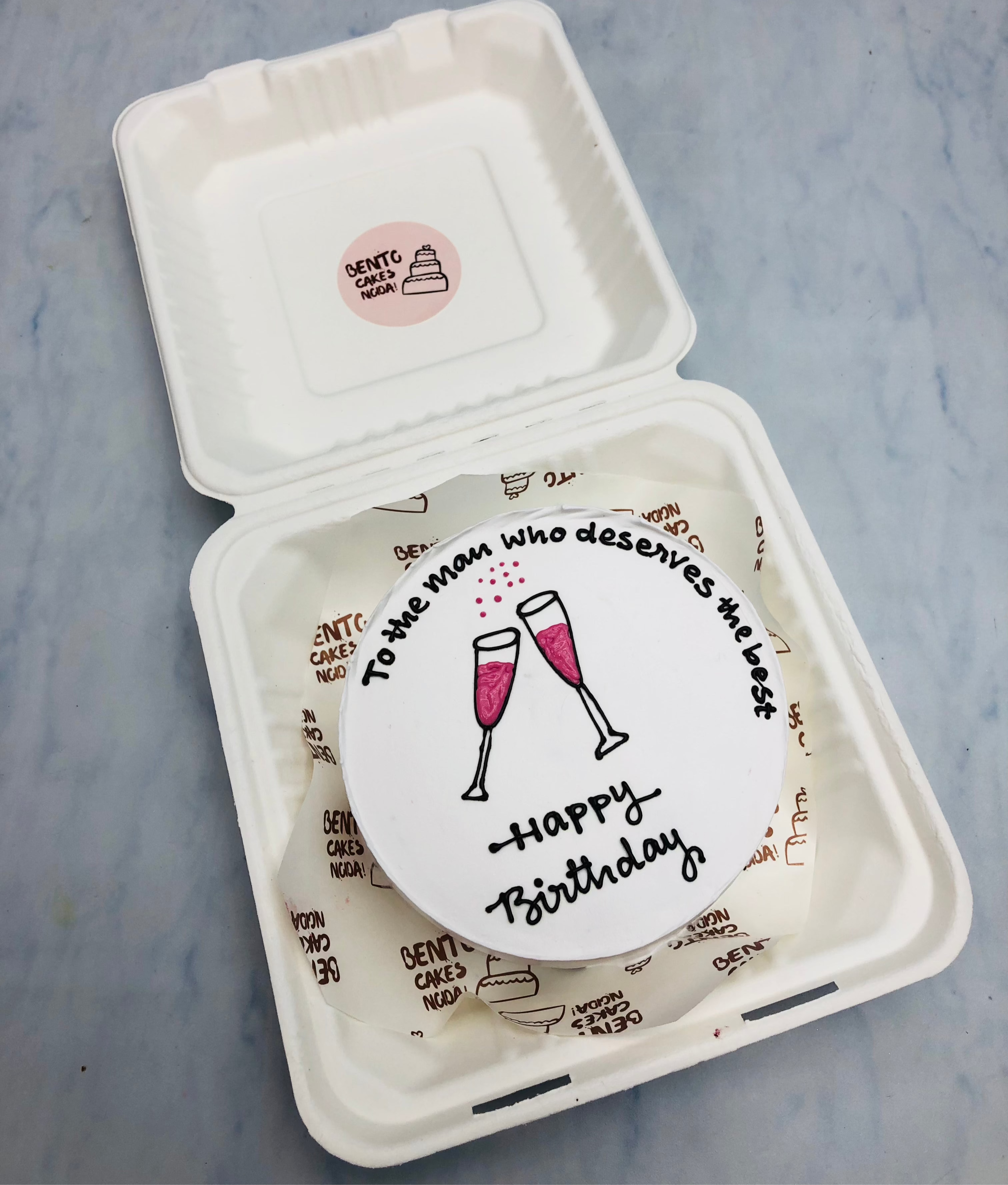 A white bento cake designed with 2 cheers dlass for his birthday.