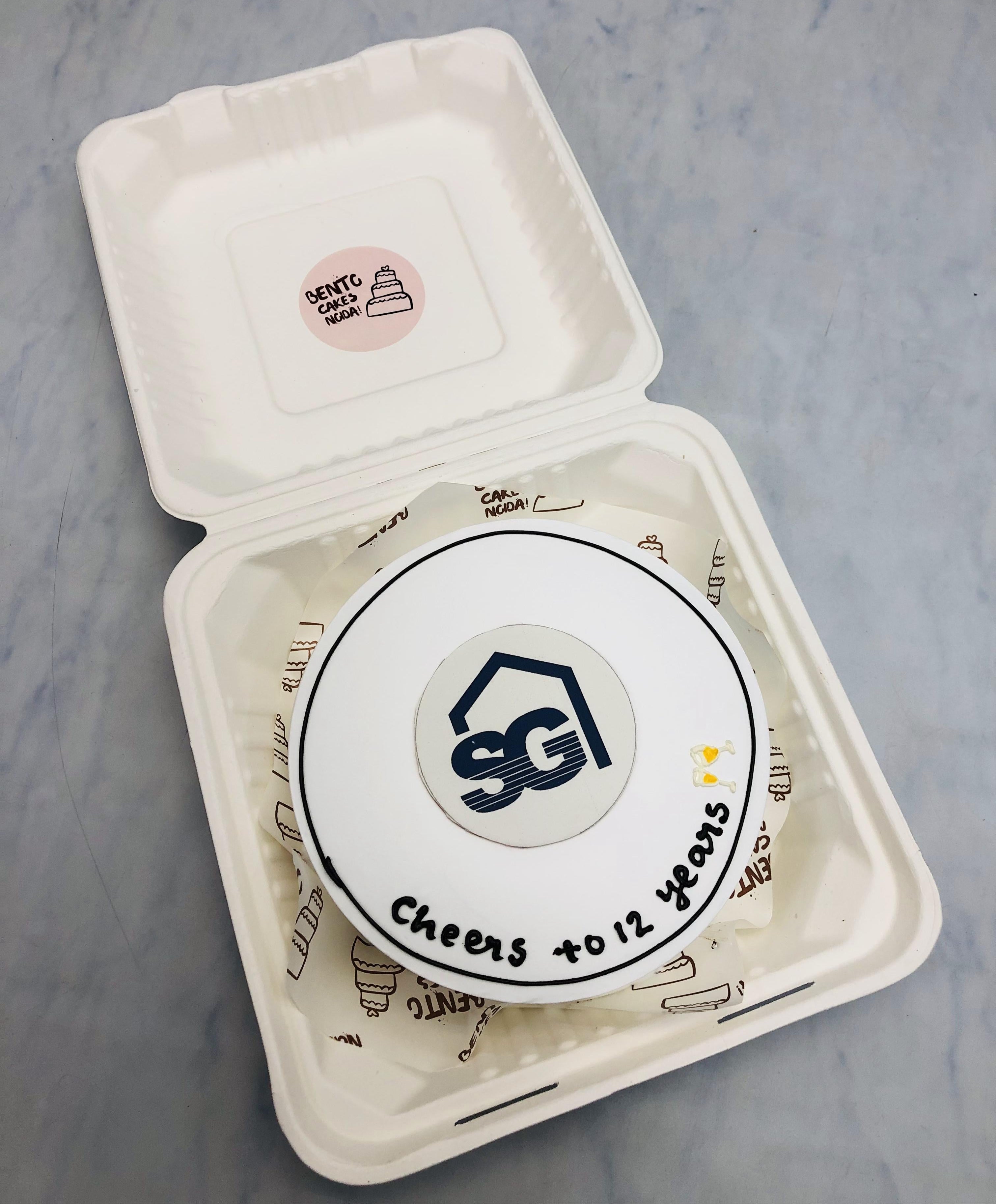 A white bento cake is designed on a commercial theme, celebrating 12 years.