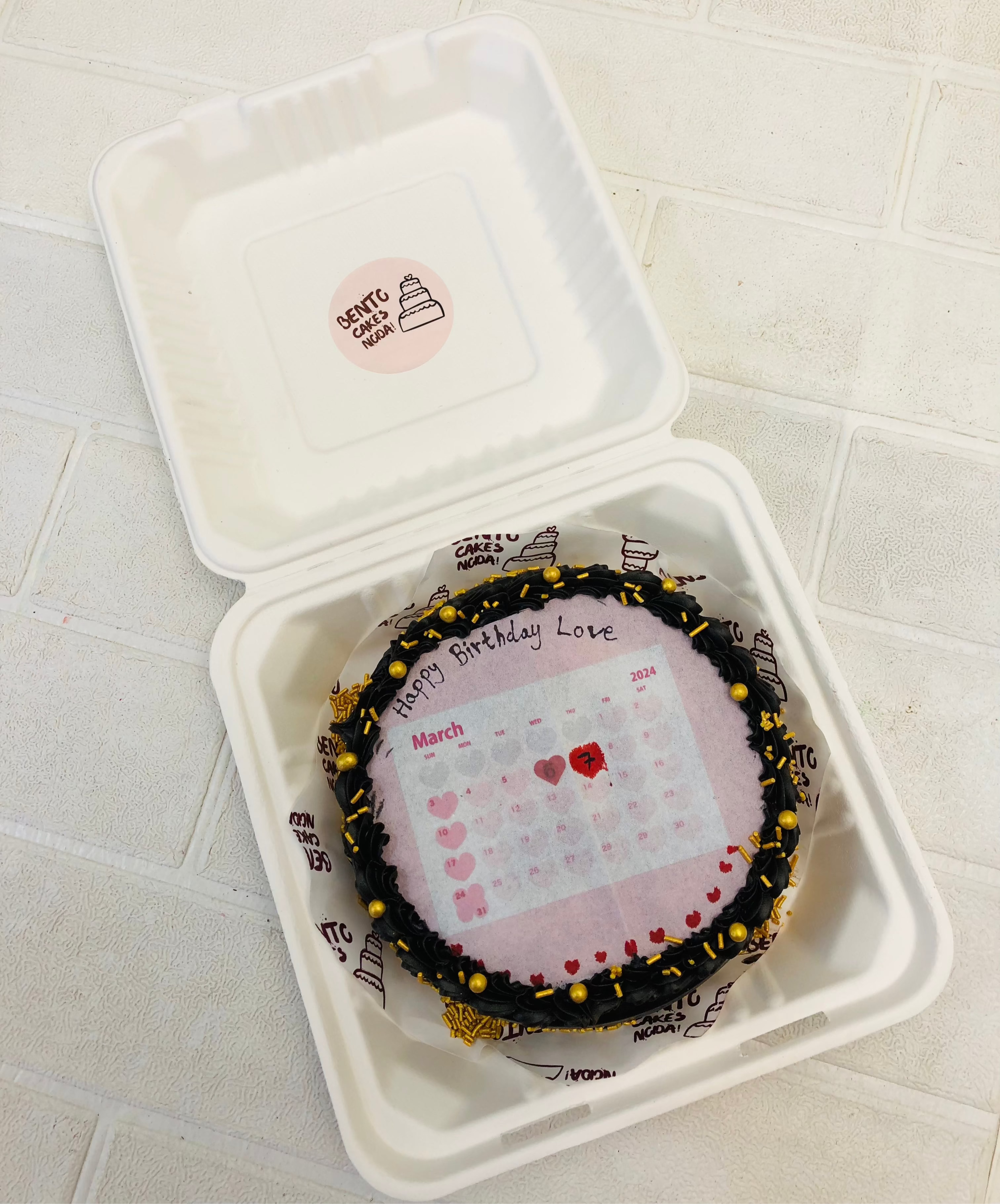 A chocolate fire bento cake with calendar heart theme and decorated with golden sprinkles.