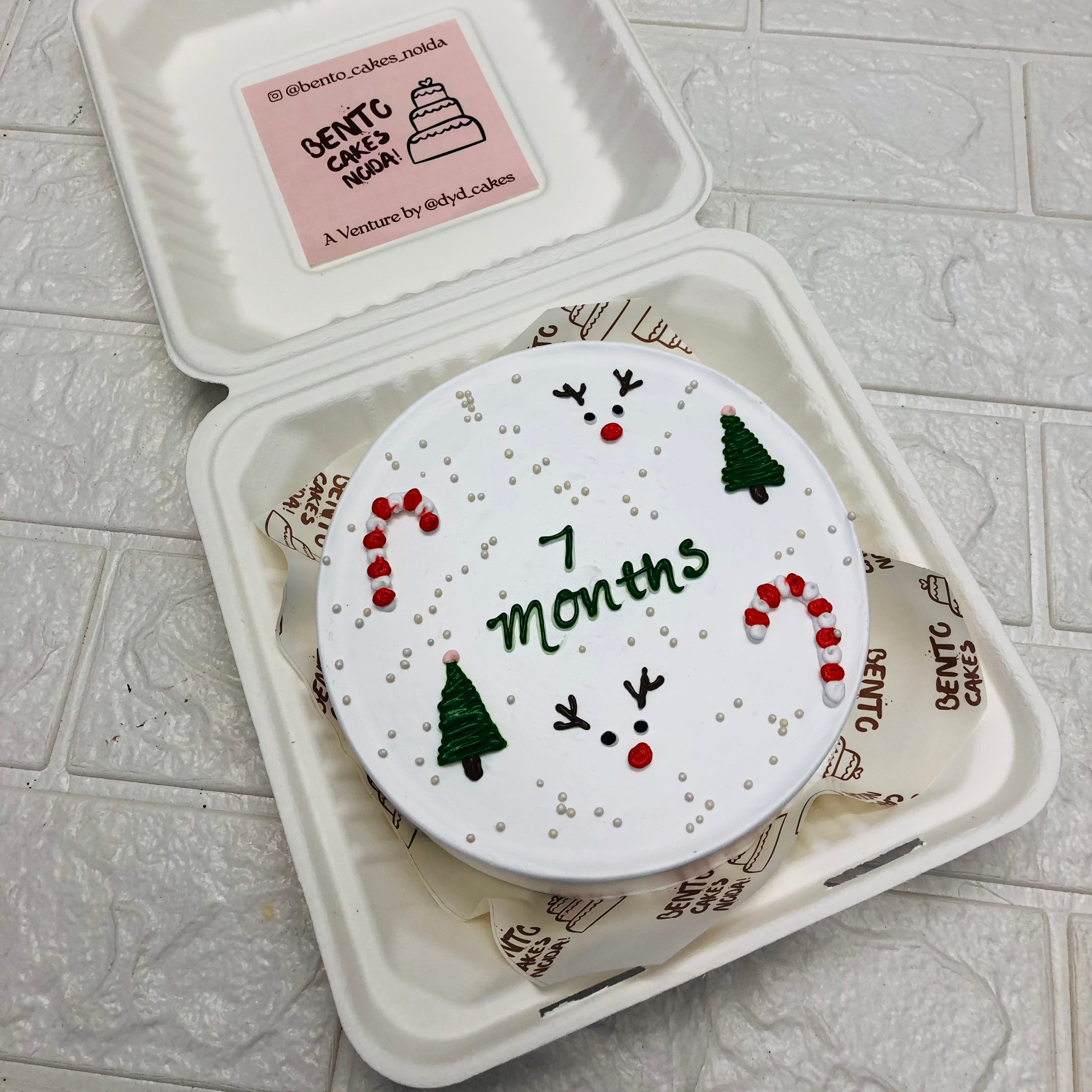 A white bento cake designed on christmas theme for a 7 months baby.