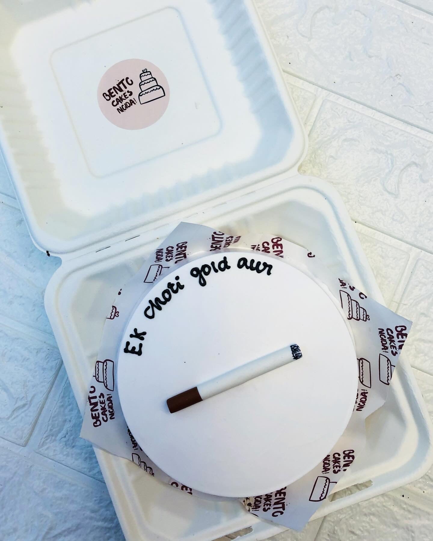A cigarette designed with fonant on a white bento cake with a message.