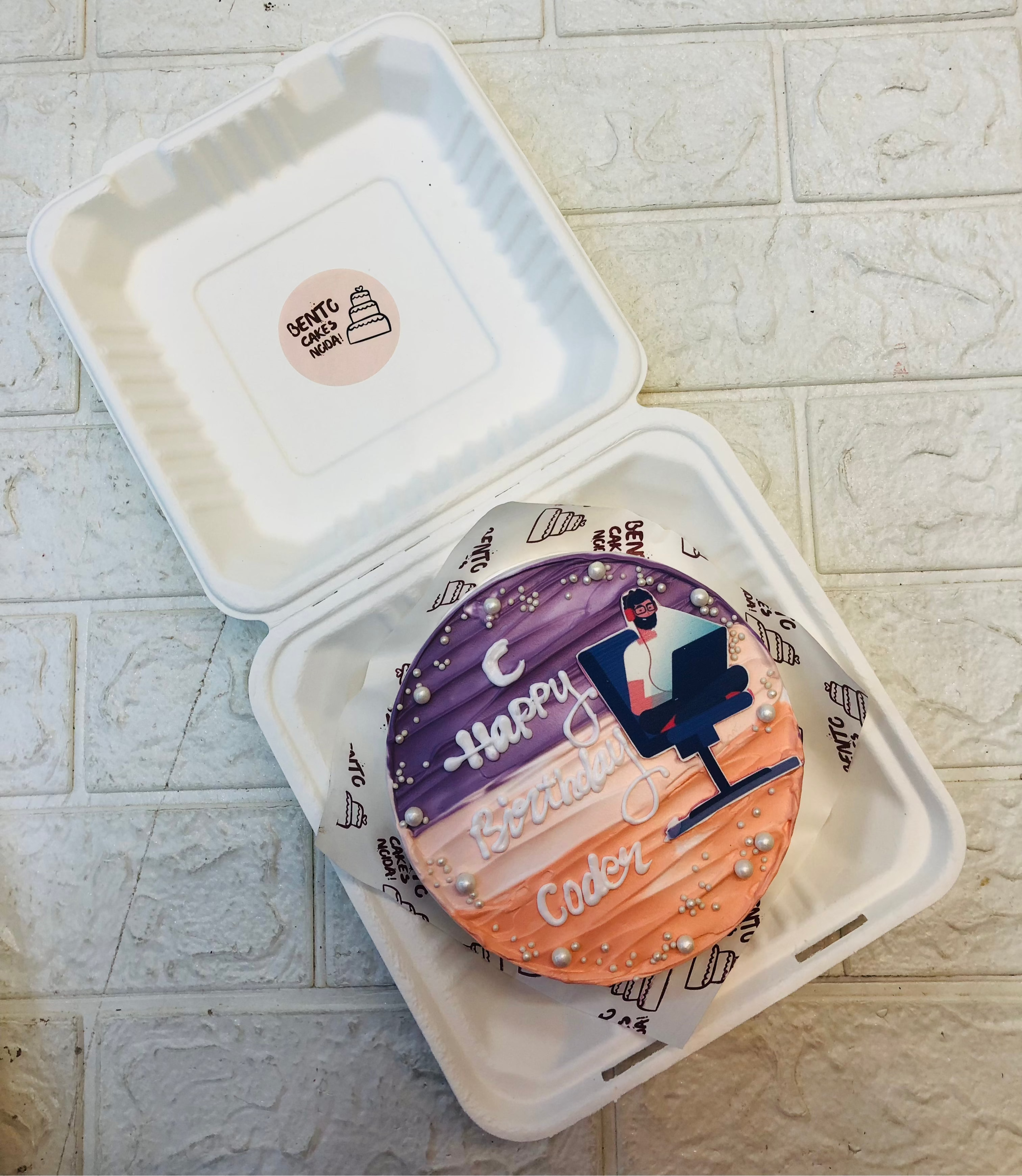 An aesthetic shades bento cake is designed for a coder's birthday a sticker of a men working on his laptop.