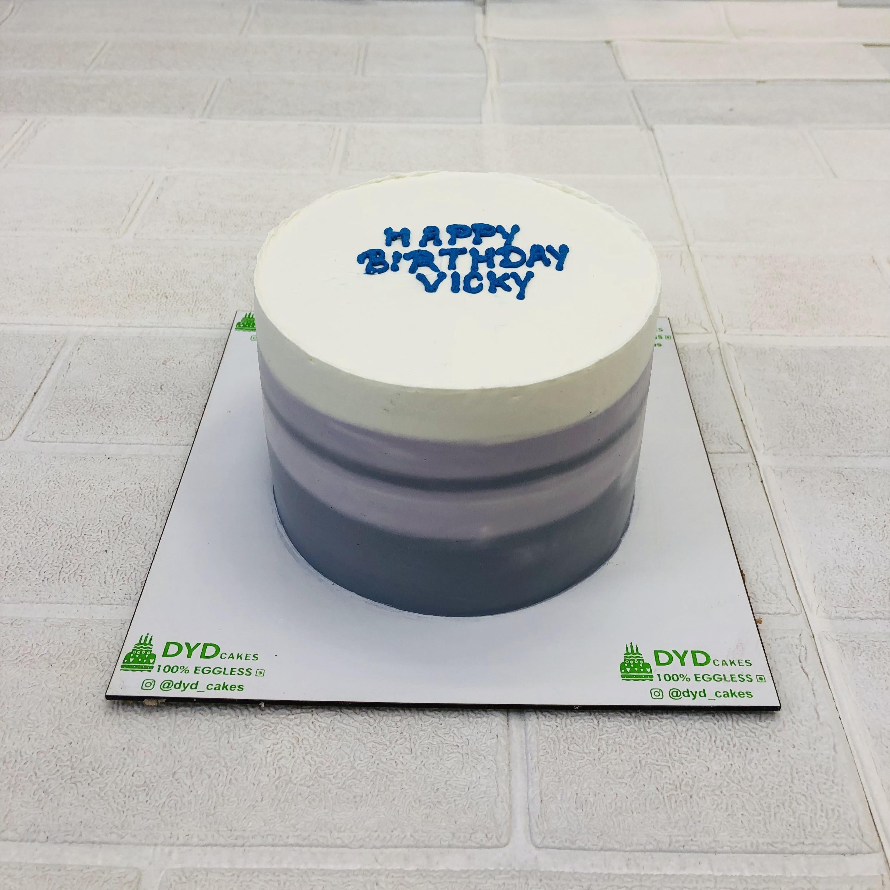 A white cake designed with grey and purple shades around it.