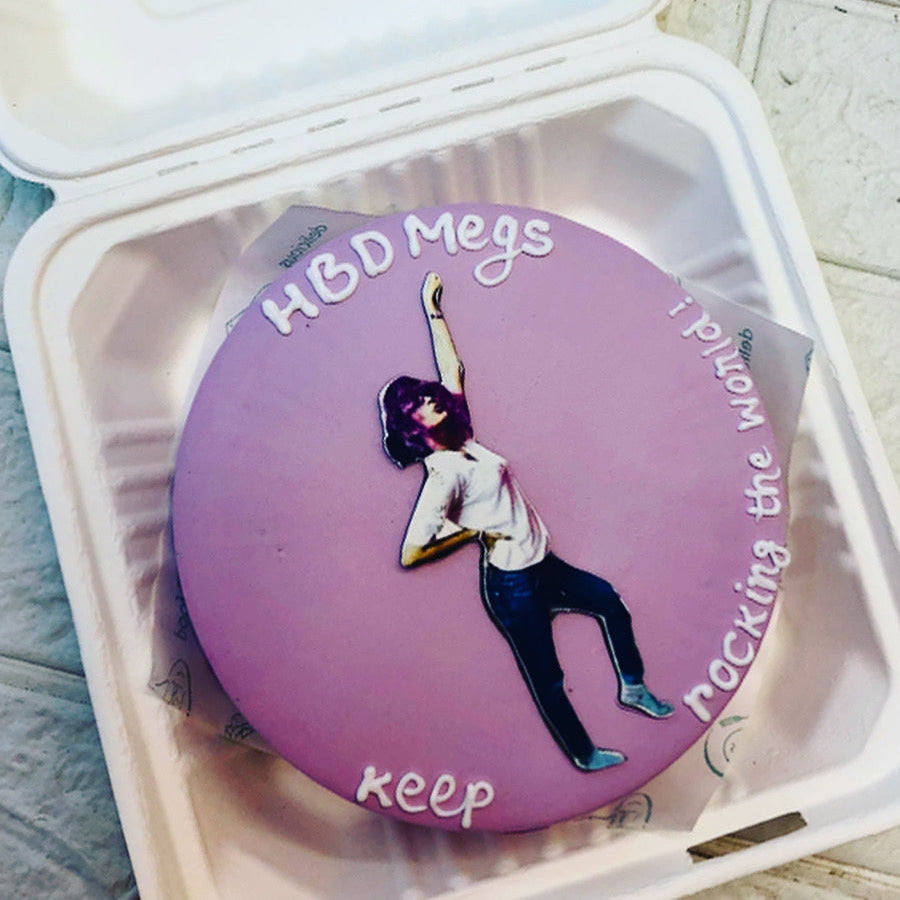  A purple icing cake is decorated with white customized  text and a pho o of standing girl placed on it.