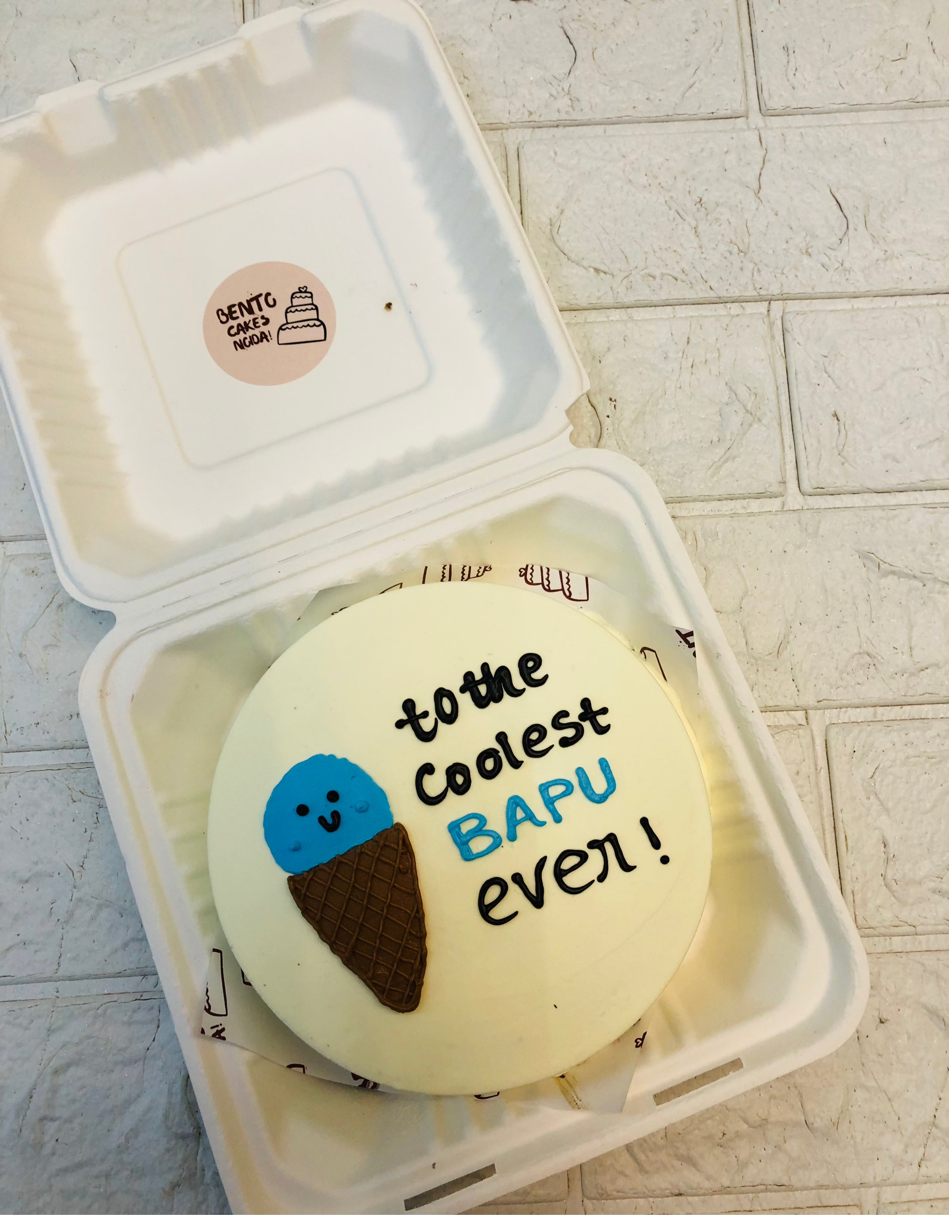 A cone icecream design on a white bento cake with a ool text written on cake for father.