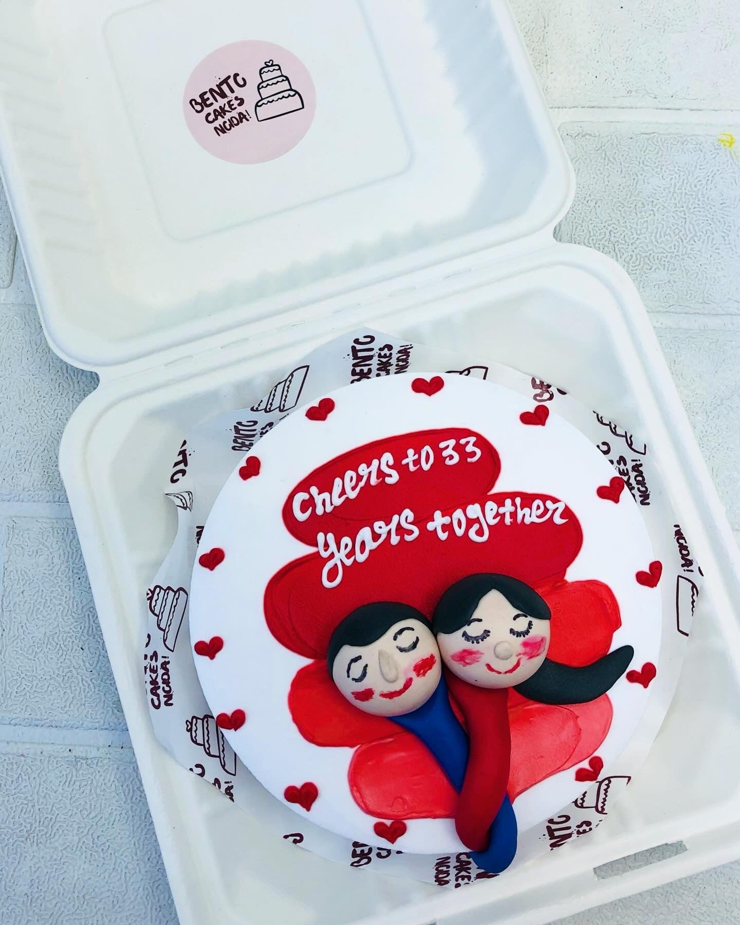Fondant couple face design on shady red bento cake for anniversary.