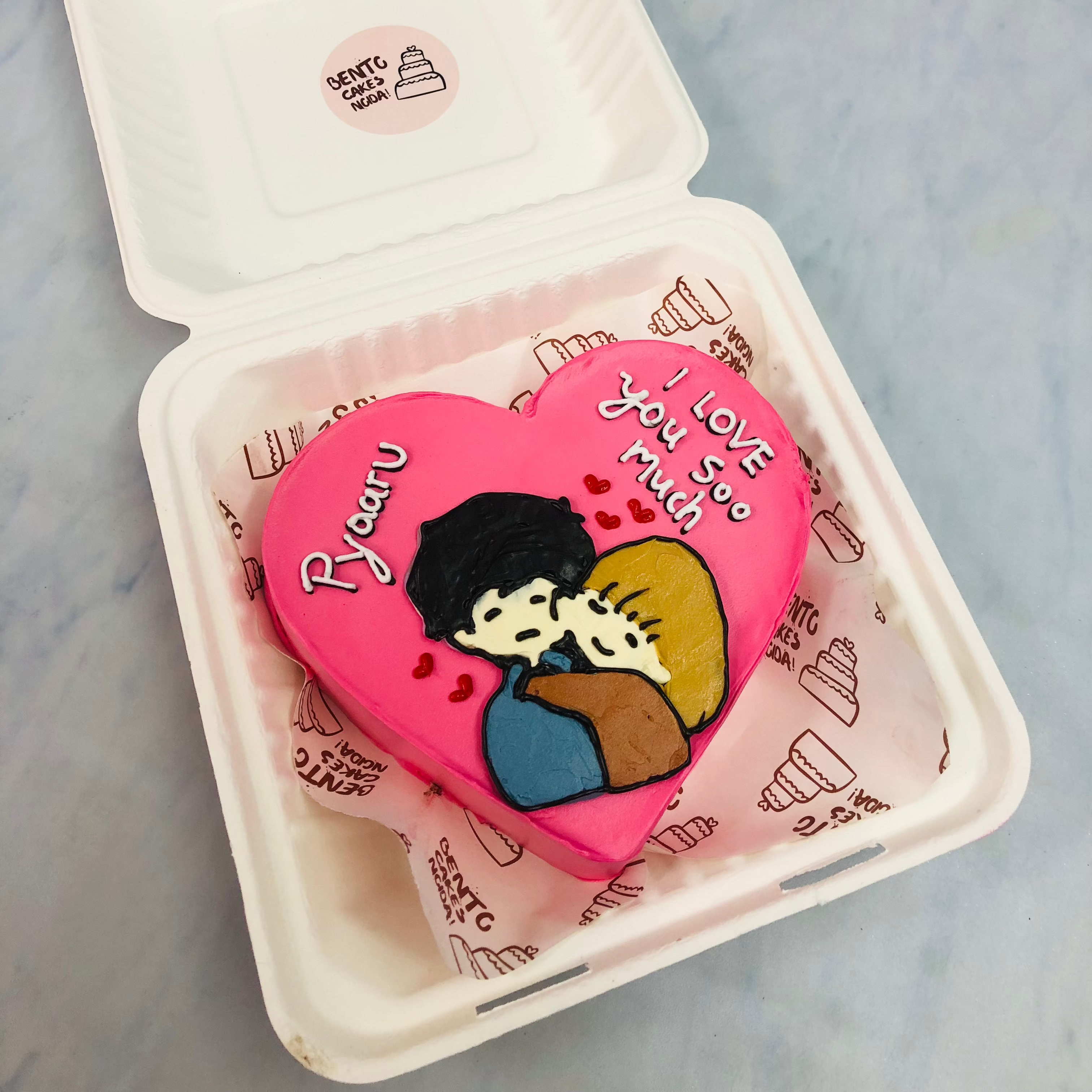 A pink color heart shape cake with a hugging couple drawing on it.