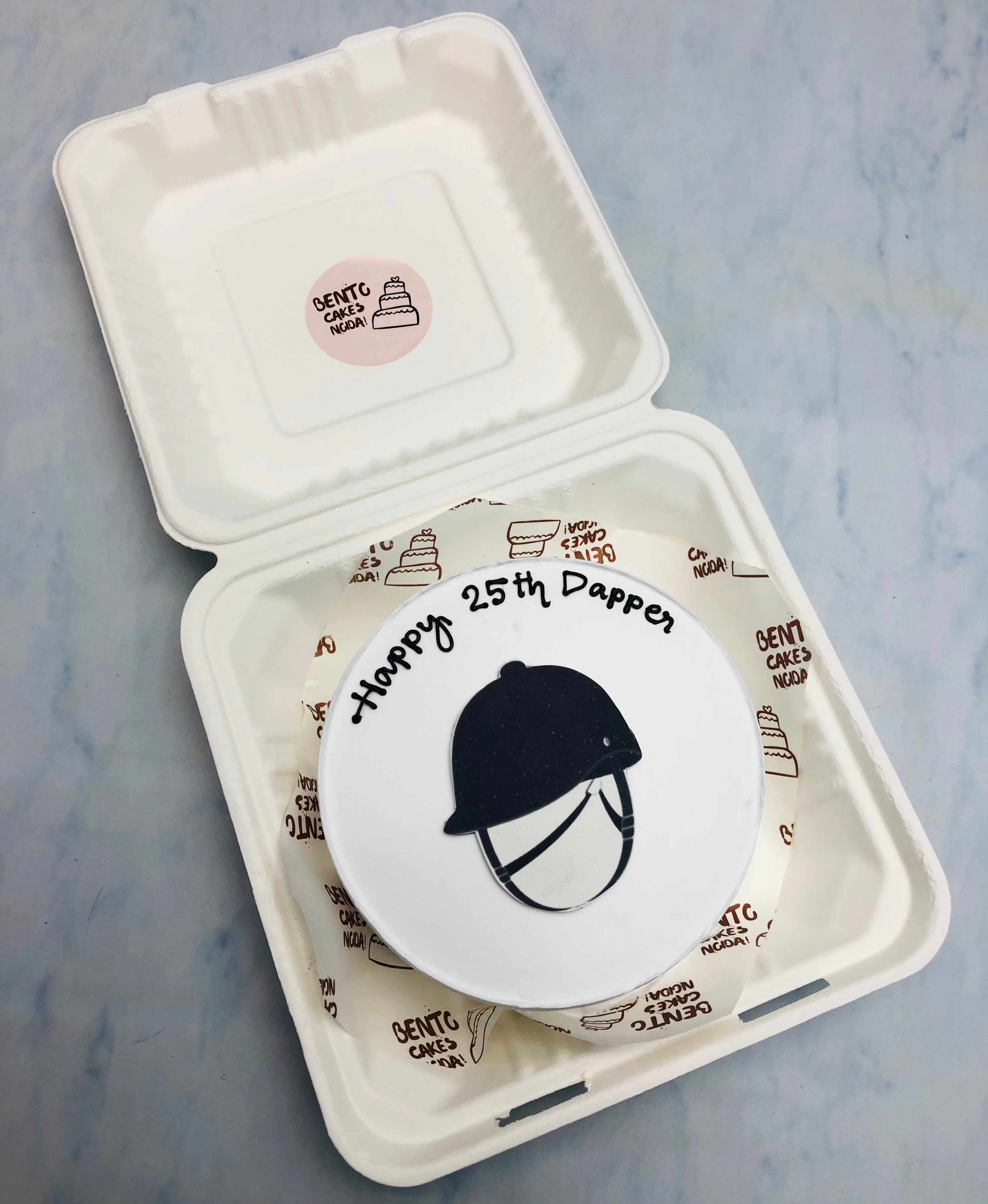 A white bento cake with a cricket helmet print for cricket lover's birthday.