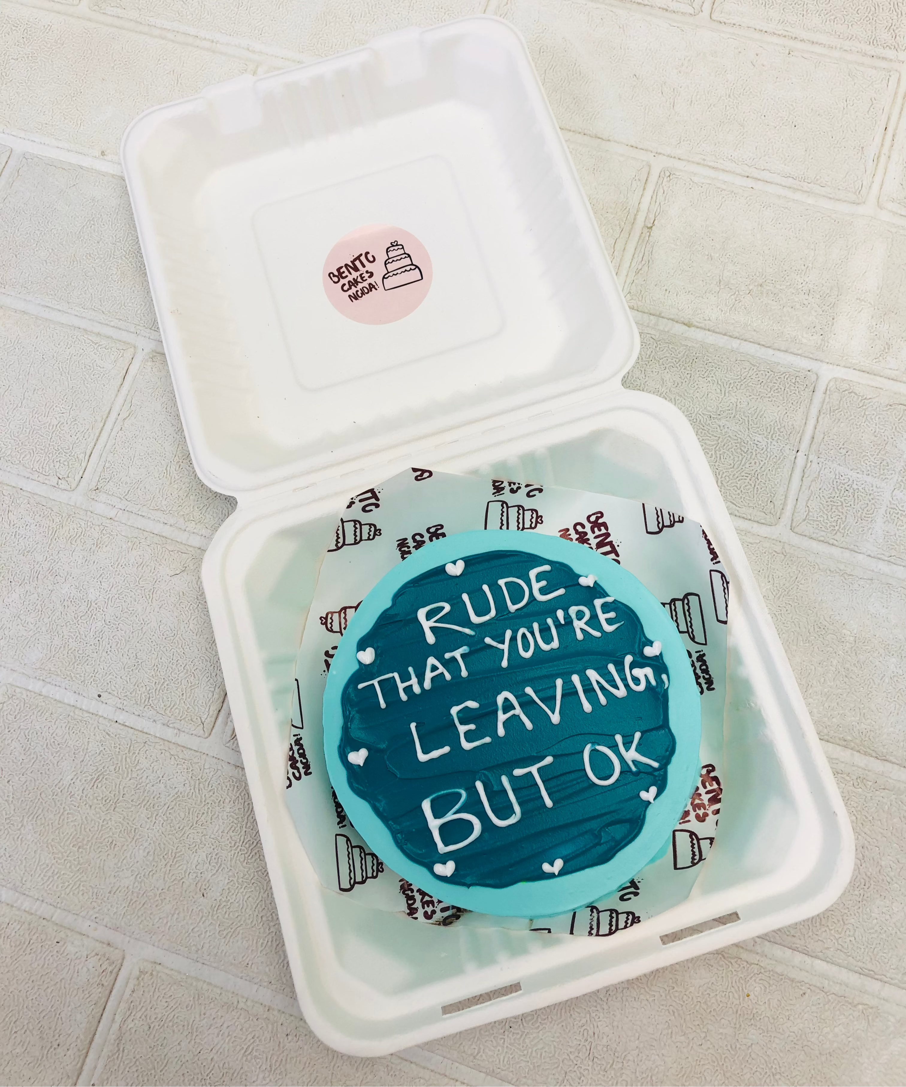 An aesthetic blue shades bento cake with a lovinga and missing text written on it.