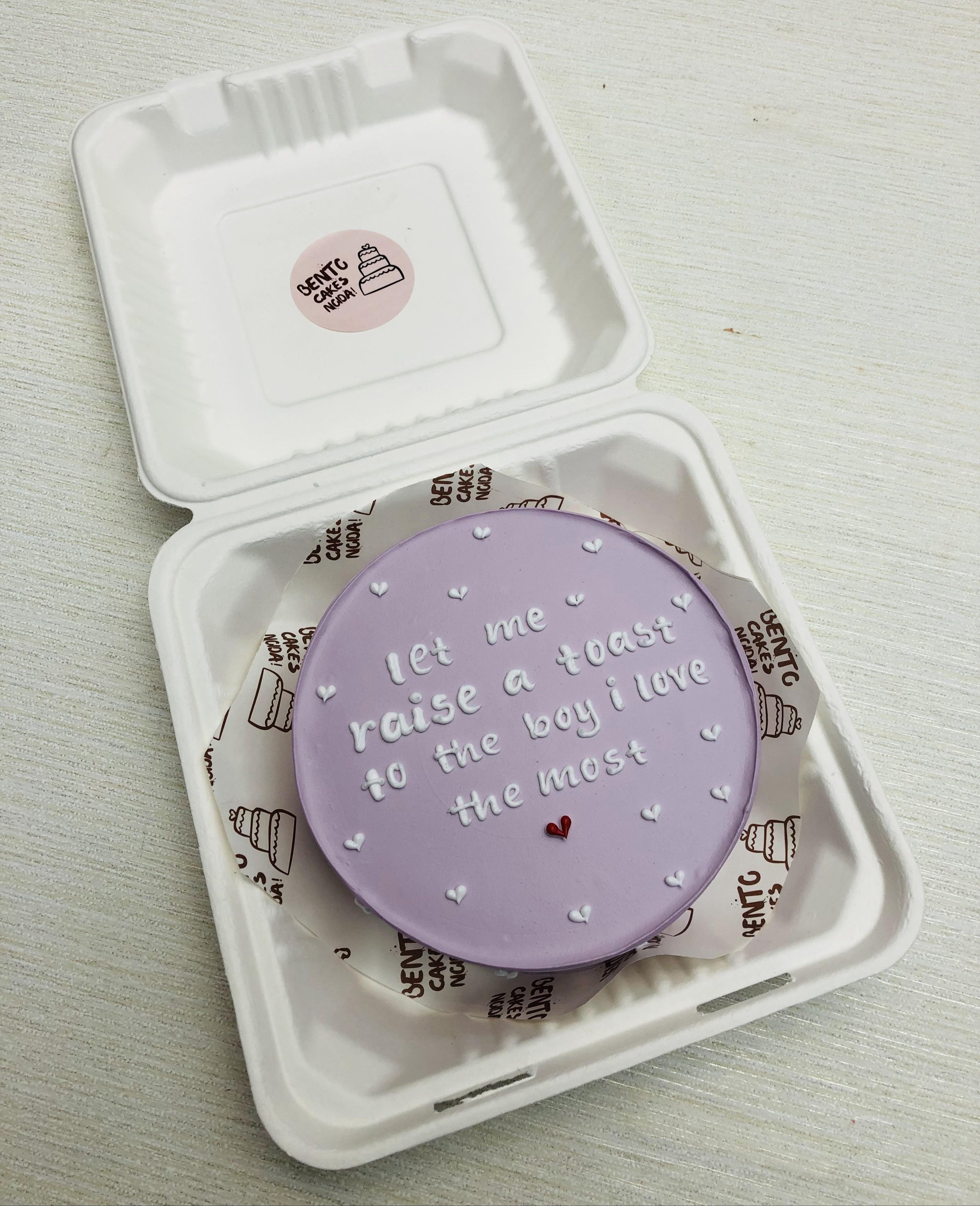 A purple bento cake having a loving message with white icing on cake.