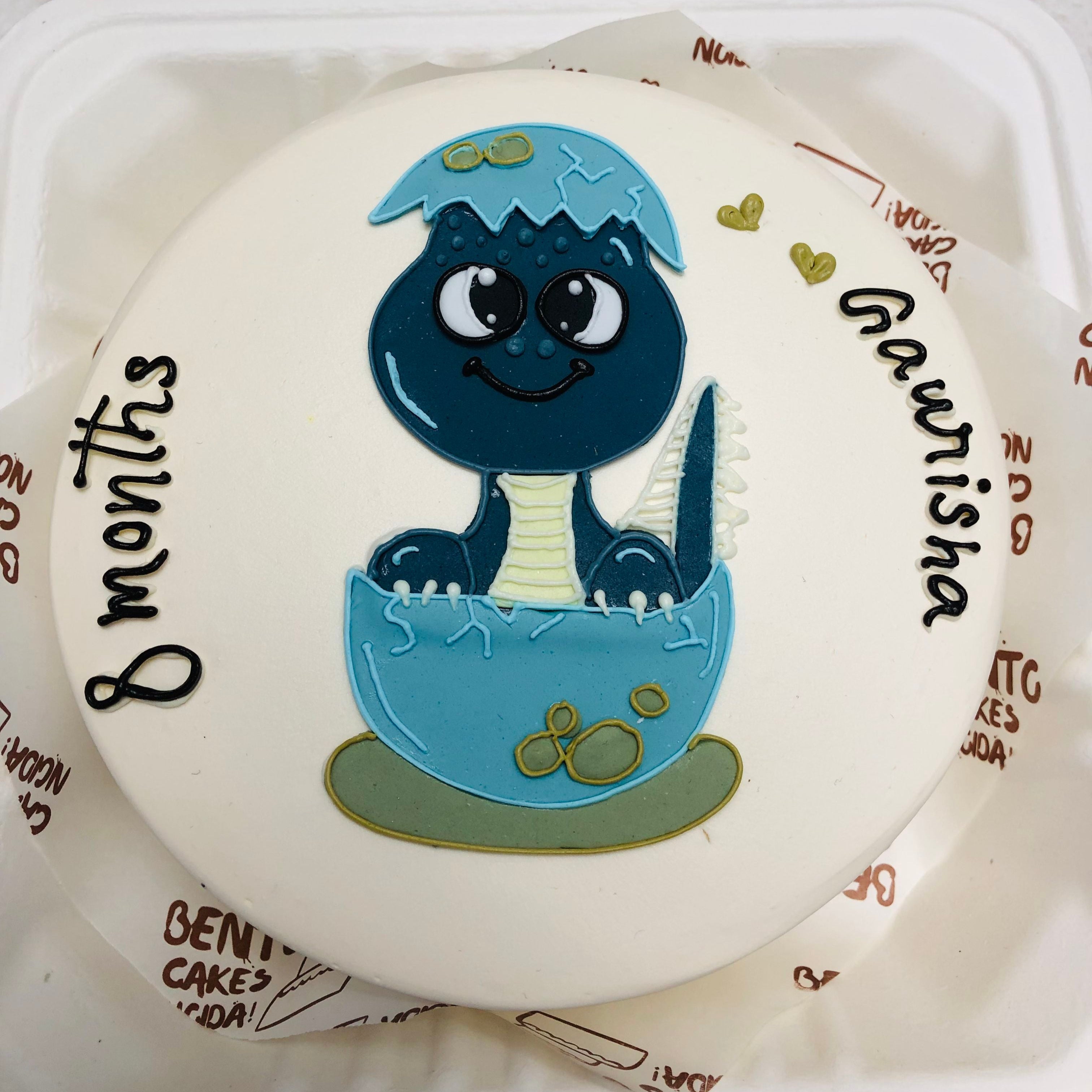 A customized cake with a blue and white cartoon, featuring the name "Gaurisha" written on the side with 8 months baby text.