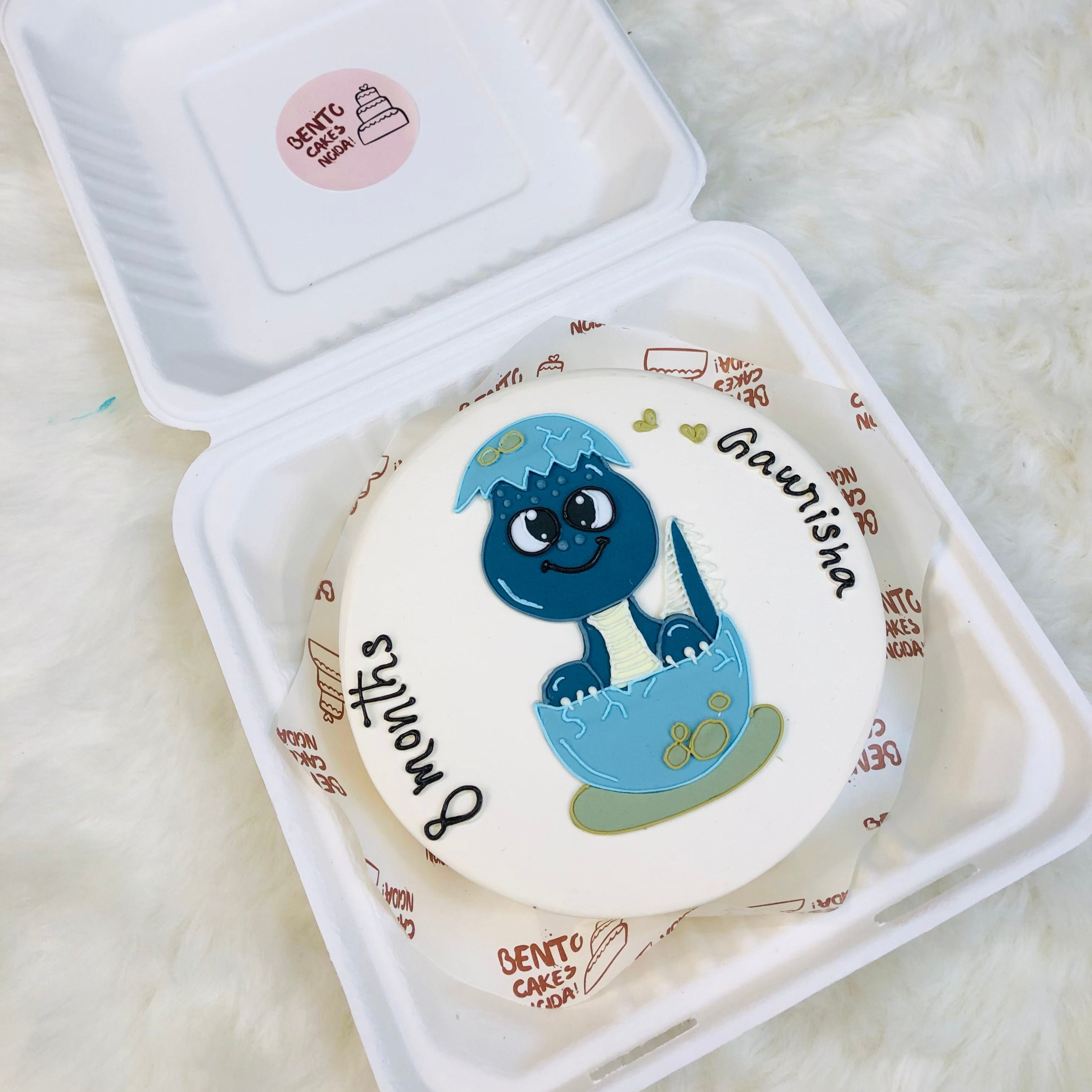 A customized cake with a blue and white cartoon, featuring the name "Gaurisha" written on the side with 8 months baby text.