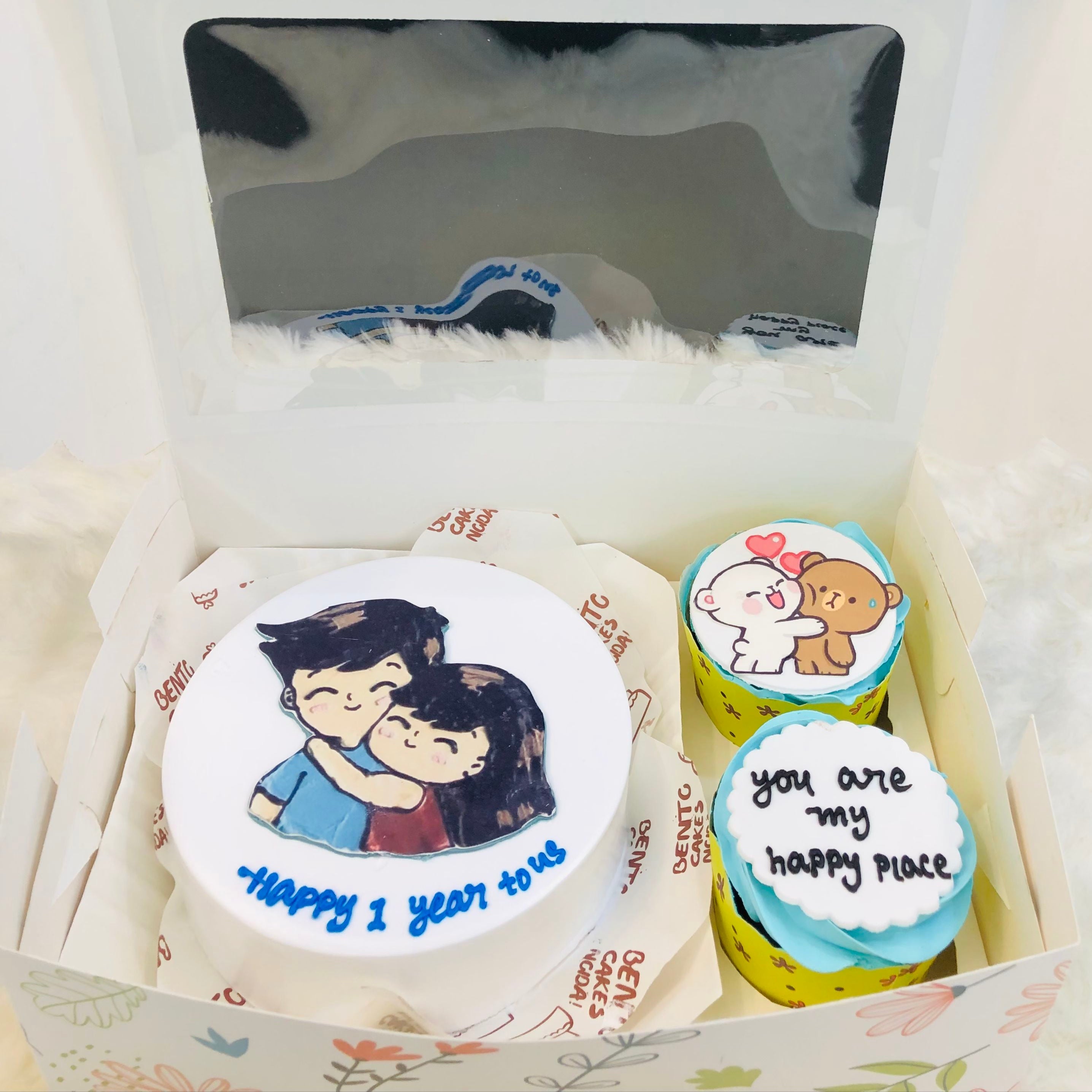 A box of colorful cupcakes adorned with a couple's figurines on top, showcasing a festive and romantic theme.