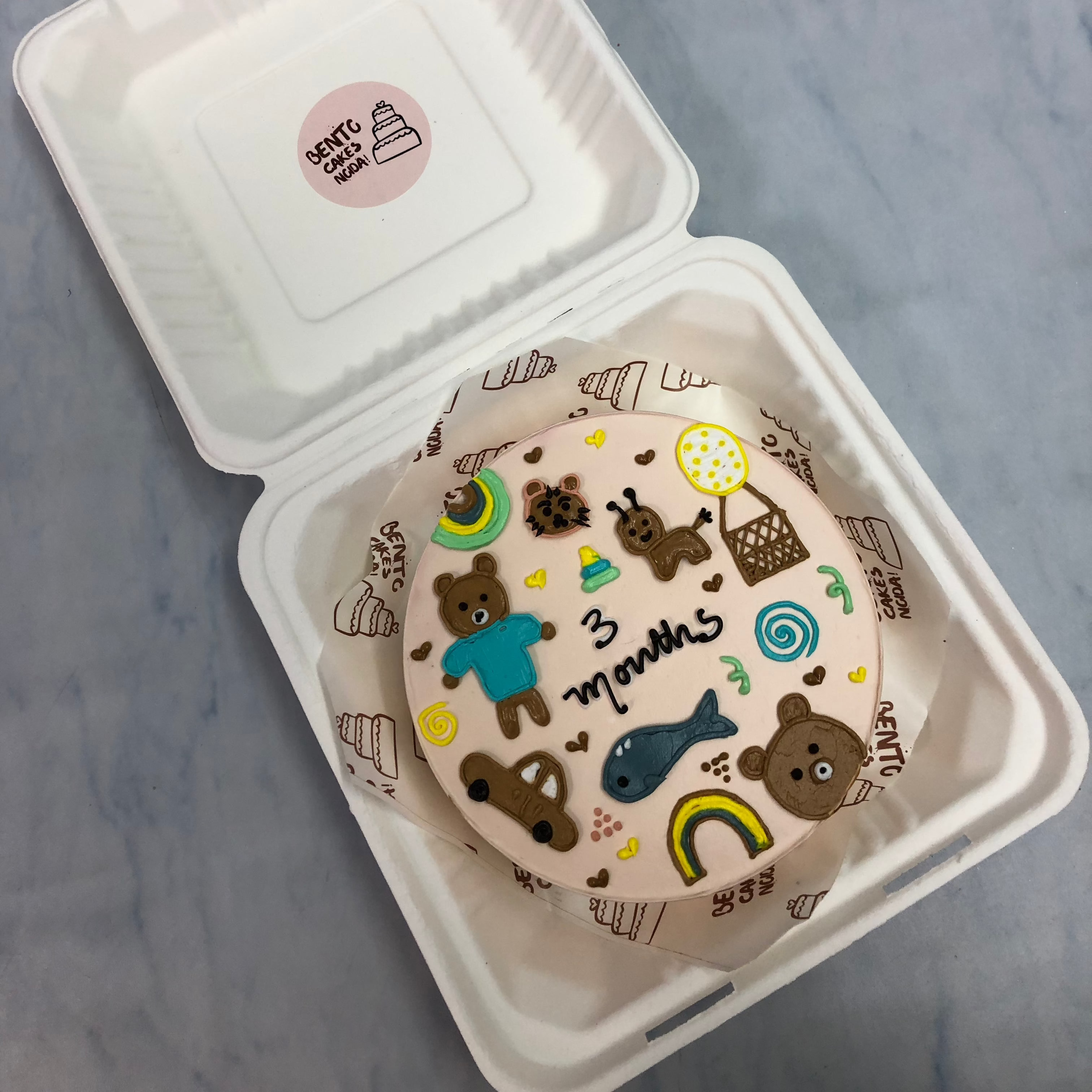 A peach color bento cake with baby toys theme.