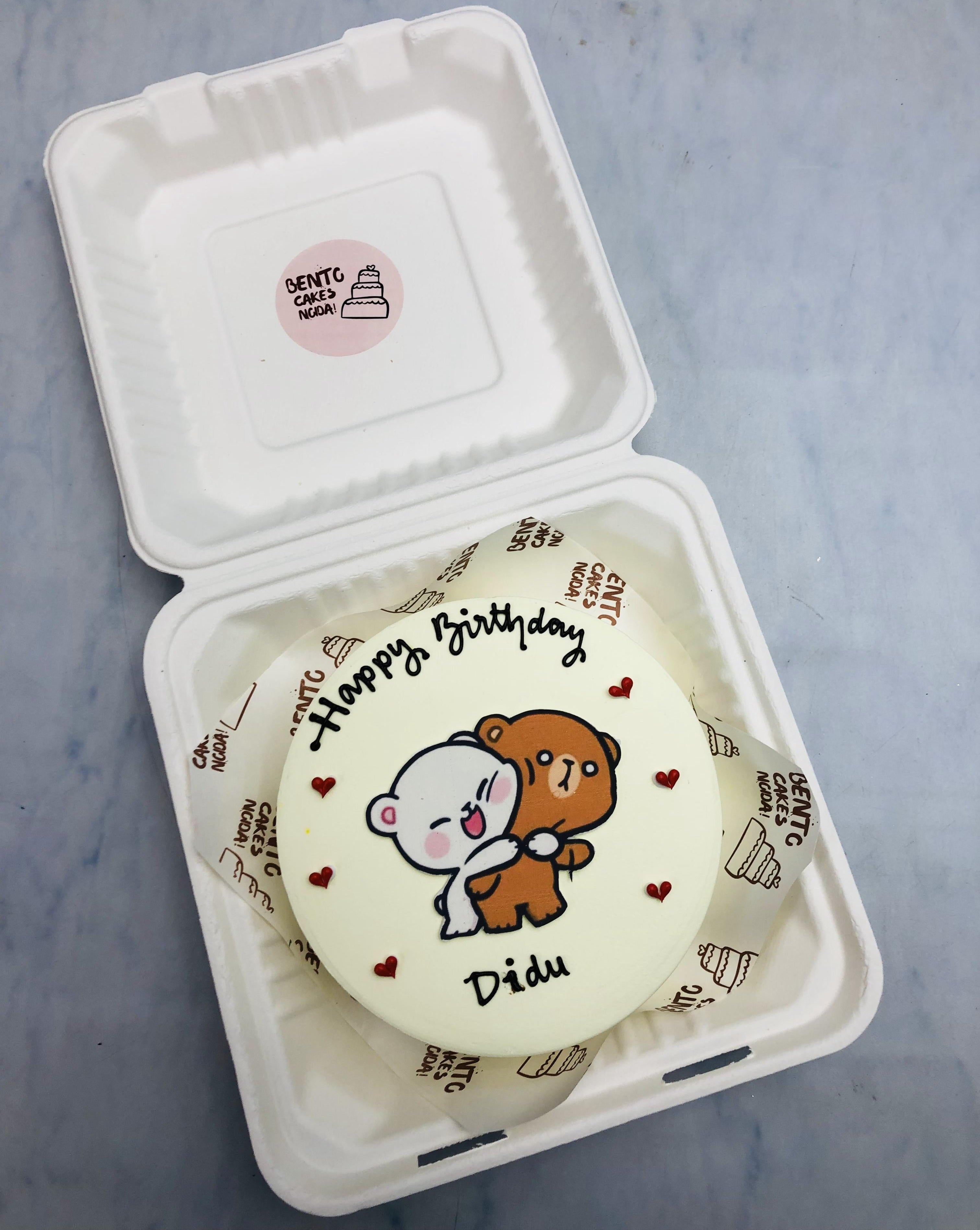 An offwhite bento cake having hugging bubu dudu cartoon print and decorated with pretty red hearts.