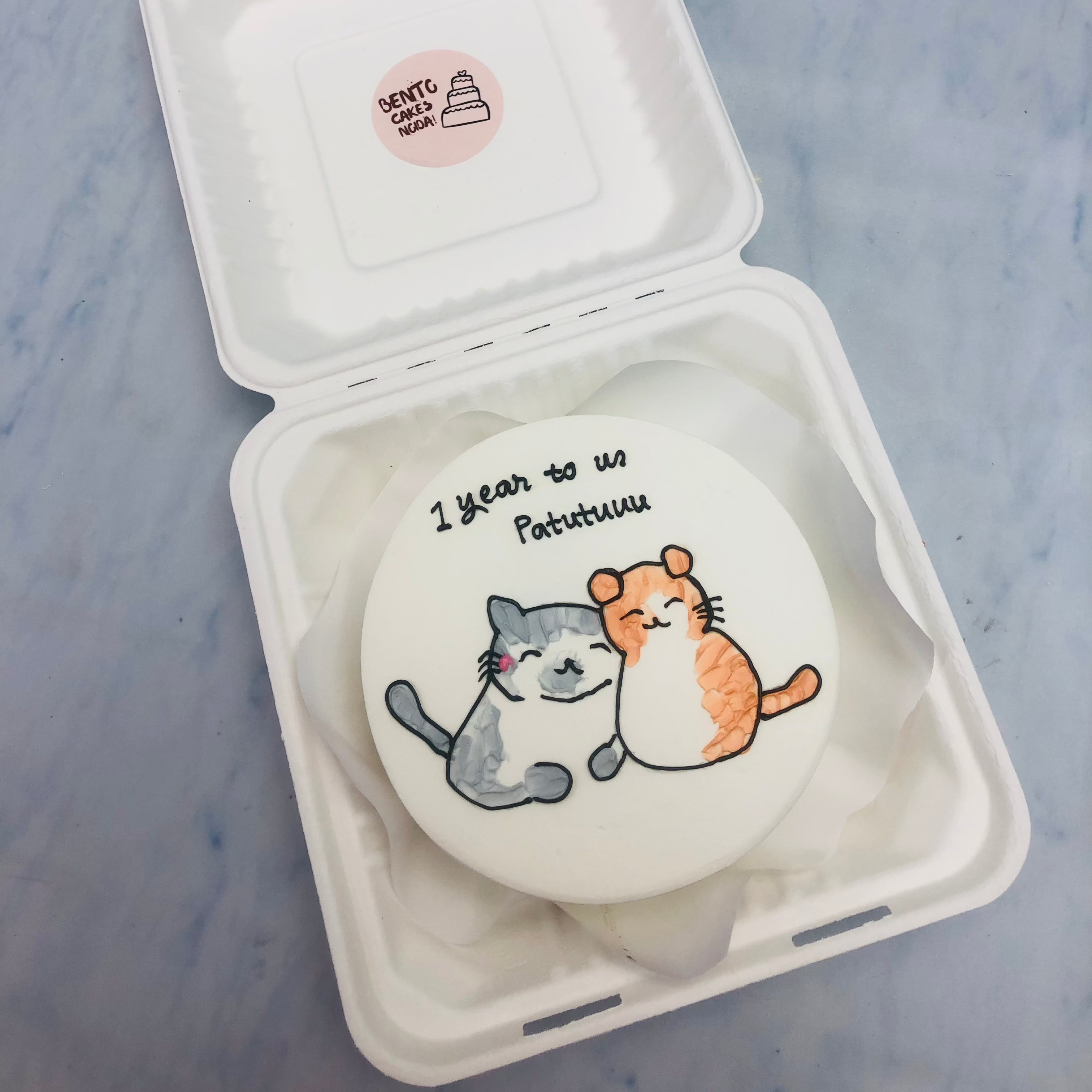 A white cake with 2 cite cats print on it.