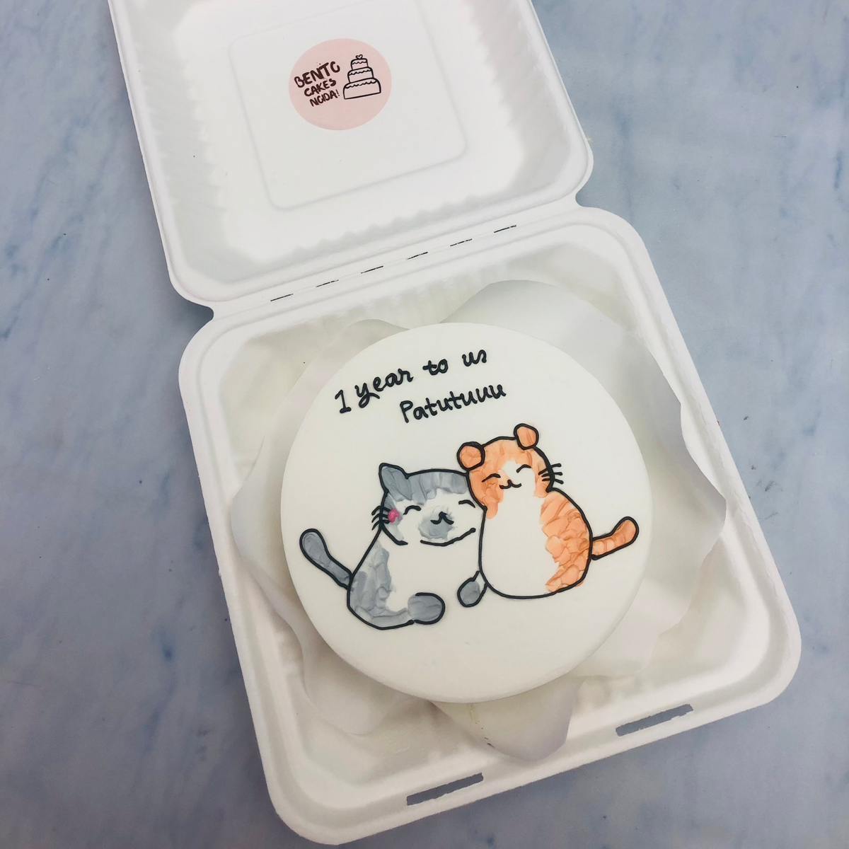 A white cake with 2 cite cats print on it.