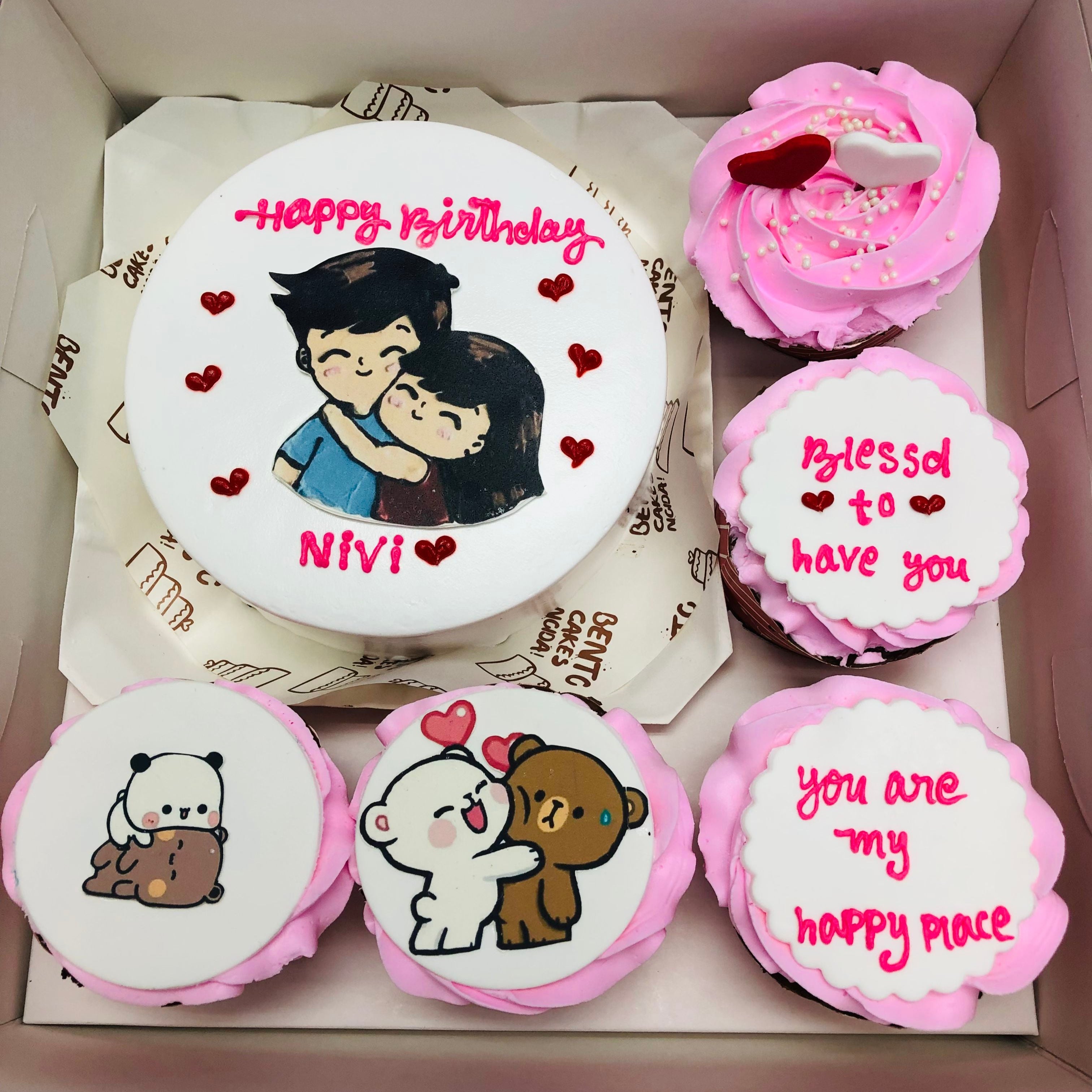 A box of colorful cupcakes featuring a cartoon couple design on top, showcasing a delightful and whimsical treat.