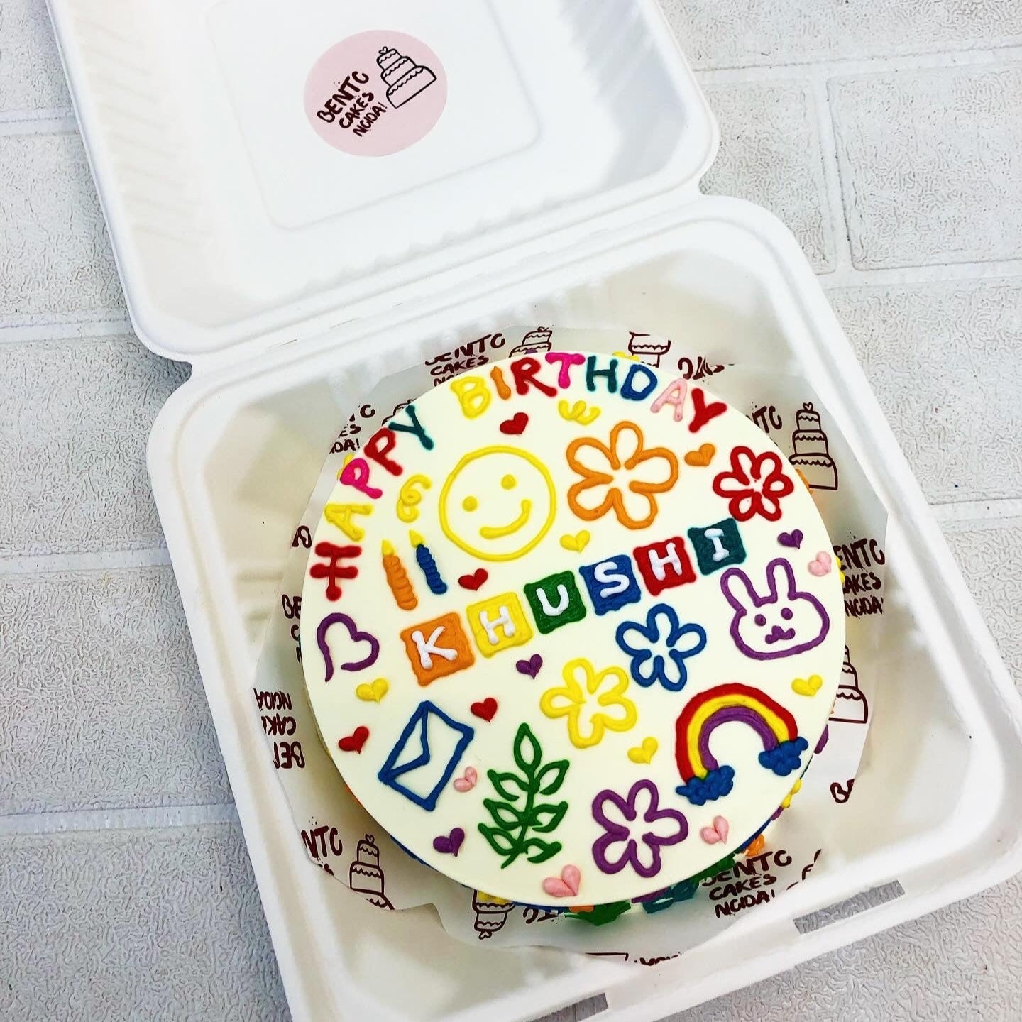 A light yellow cake designed with cute faces and floral design all over the cake.