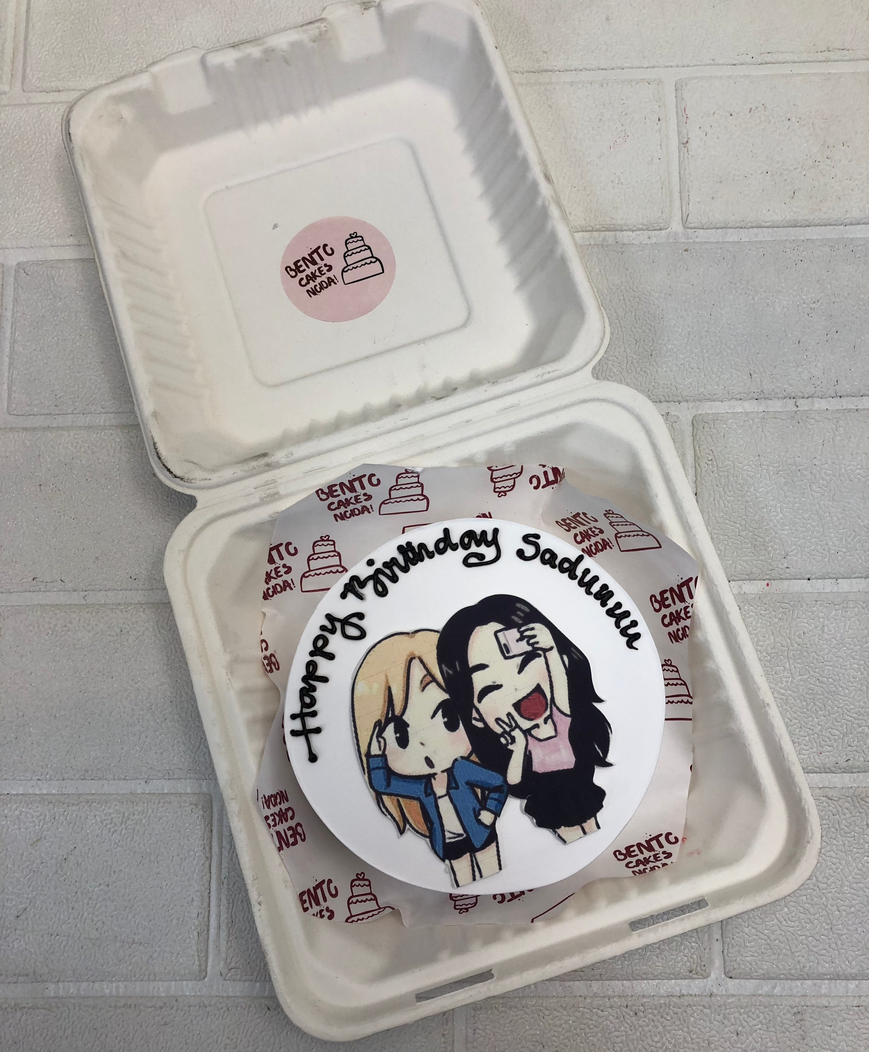 A white bento cake with two friends taking selfie.