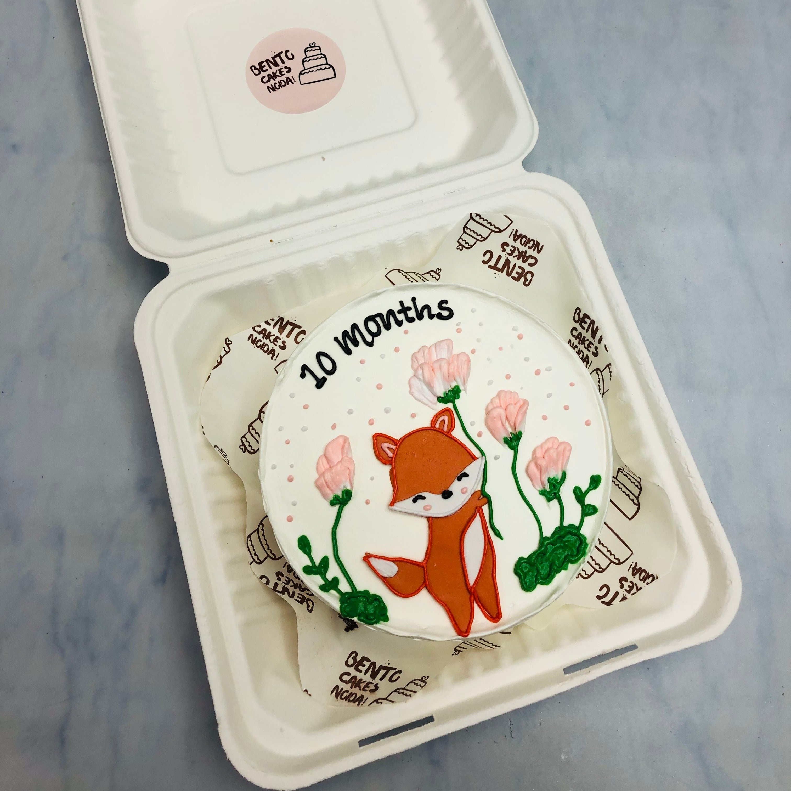 A cute squirrel drawing on a white cake with floral design for 10 months baby.